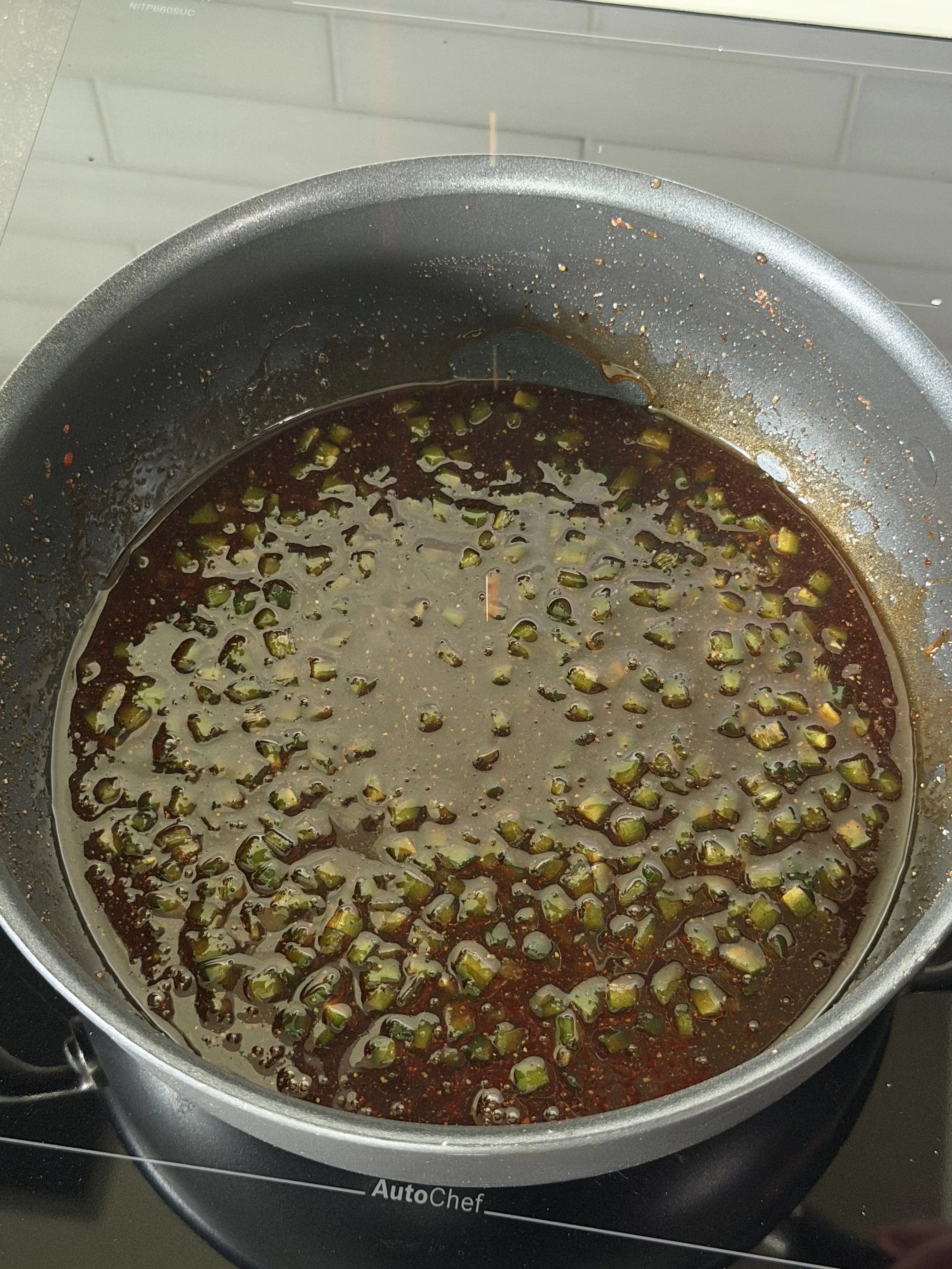 Jalapeños and aromatics sauteing in a pan for honey jalapeño sauce