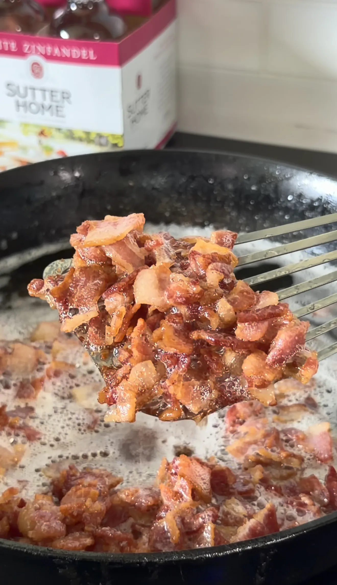 Crispy caramelized bacon being lifted with tongs from a cast iron skillet