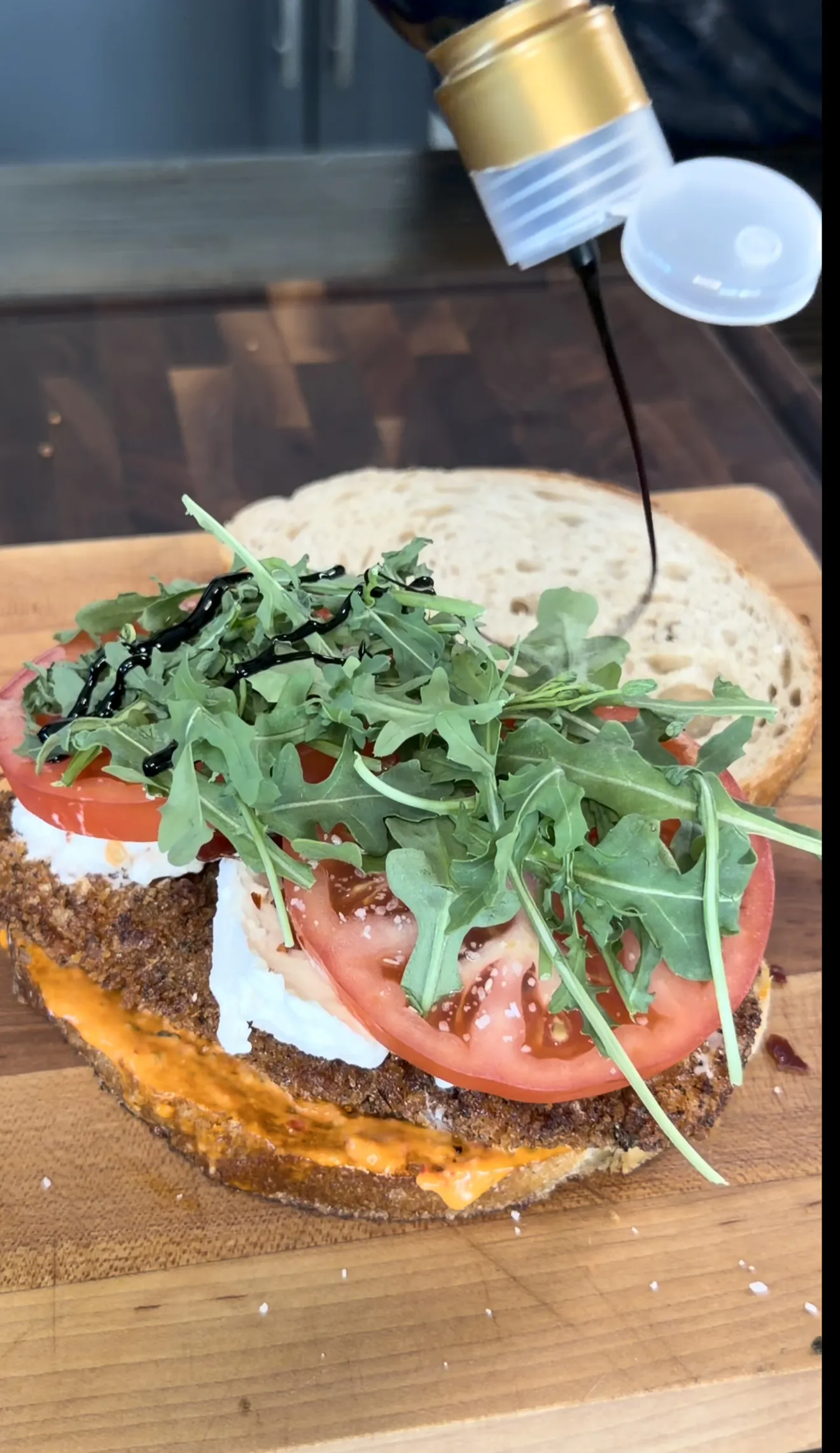 Crispy chicken cutlet sandwich topped with arugula and marinated tomato
