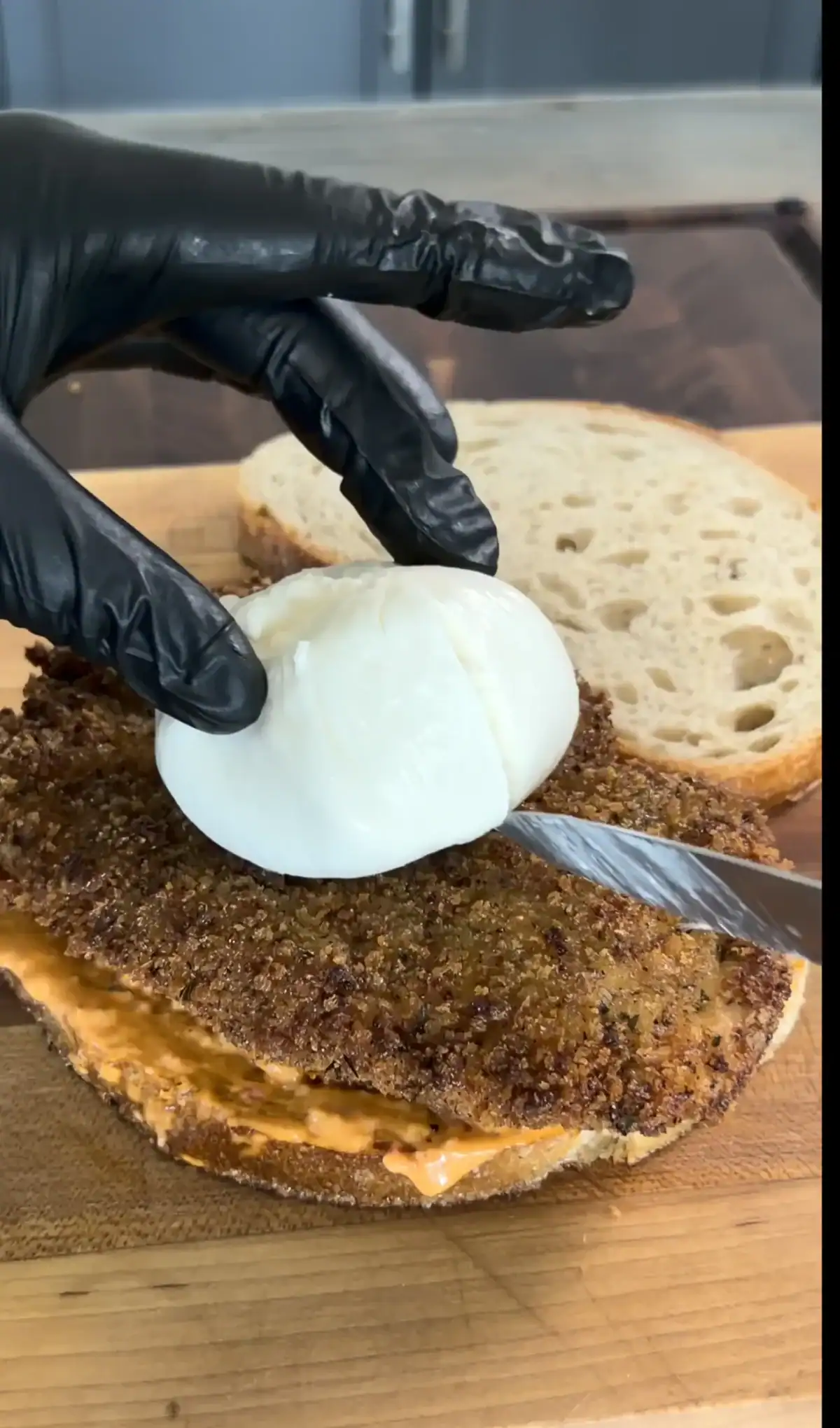 Calabrian chili mayo being spread on bread for chicken cutlet sandwich assembly