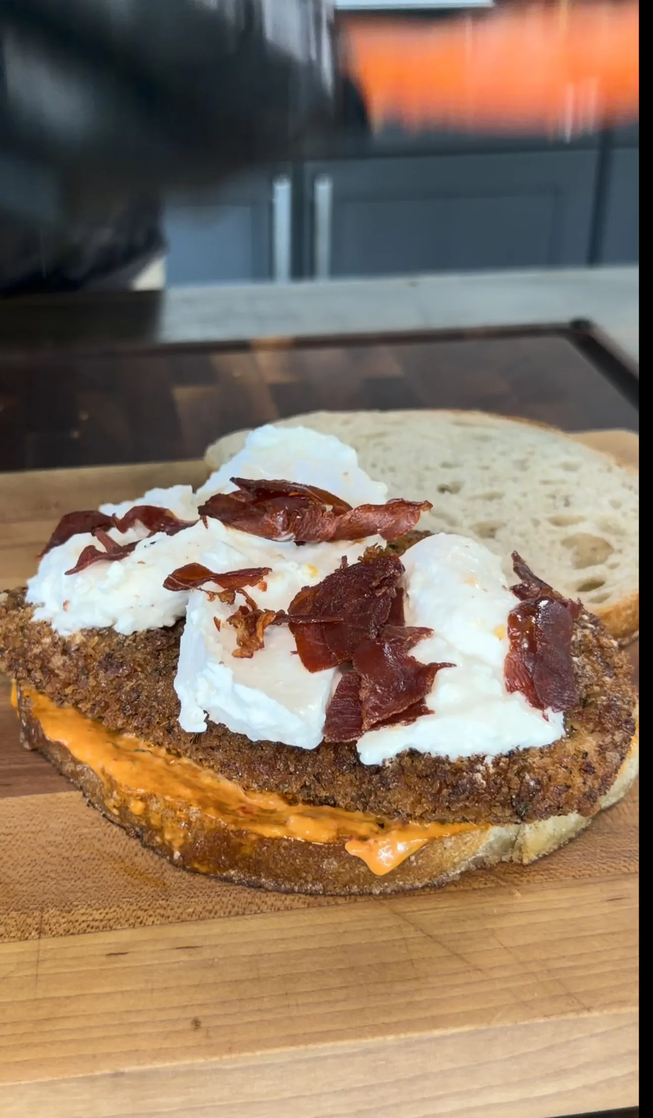 Crispy chicken cutlet sandwich being constructed on a cutting board