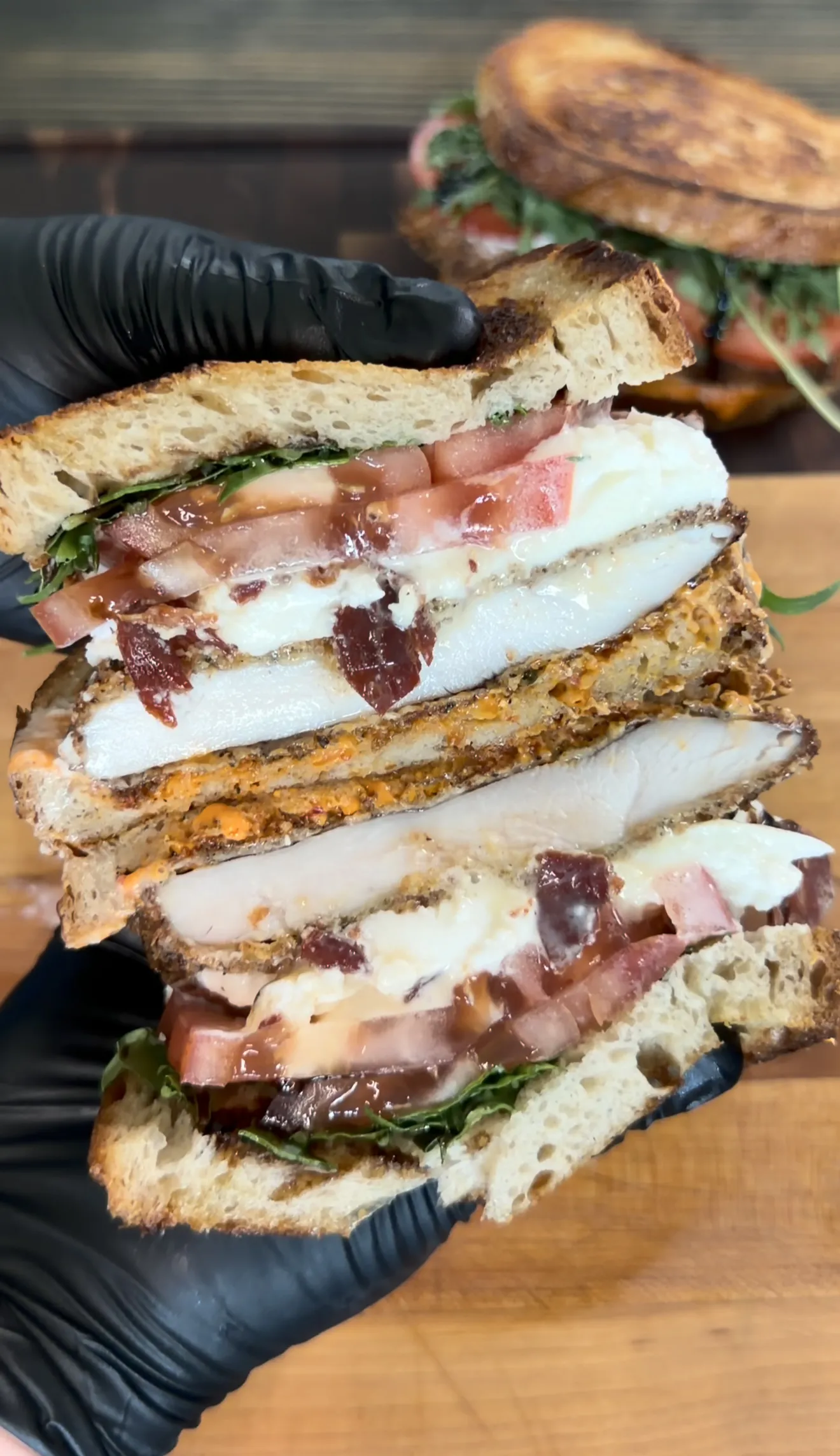 Crispy chicken cutlet sandwich halved on the grill showing layers