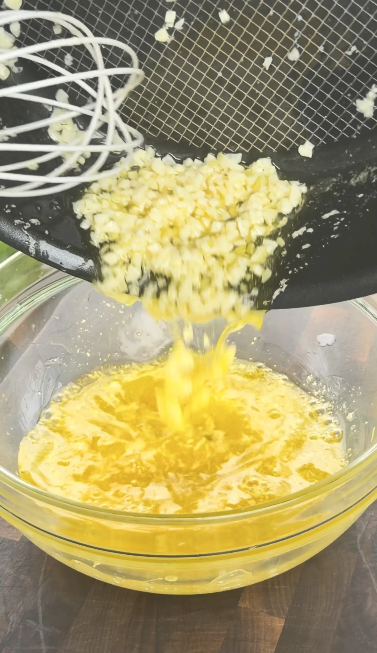 Garlic butter mixture being strained into a serving bowl