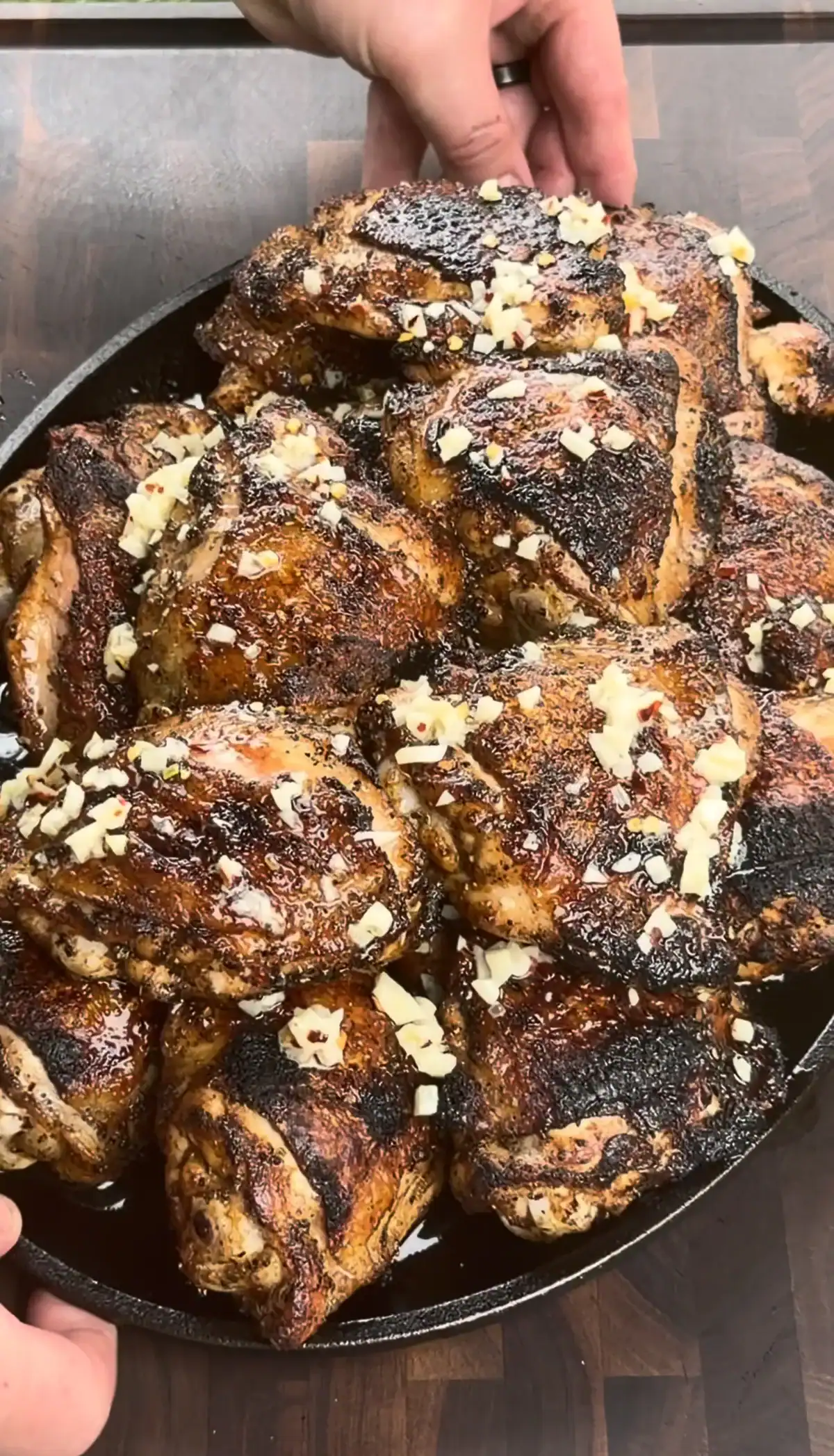 Golden-brown garlic parmesan chicken thighs in a cast iron skillet, garnished with grated cheese