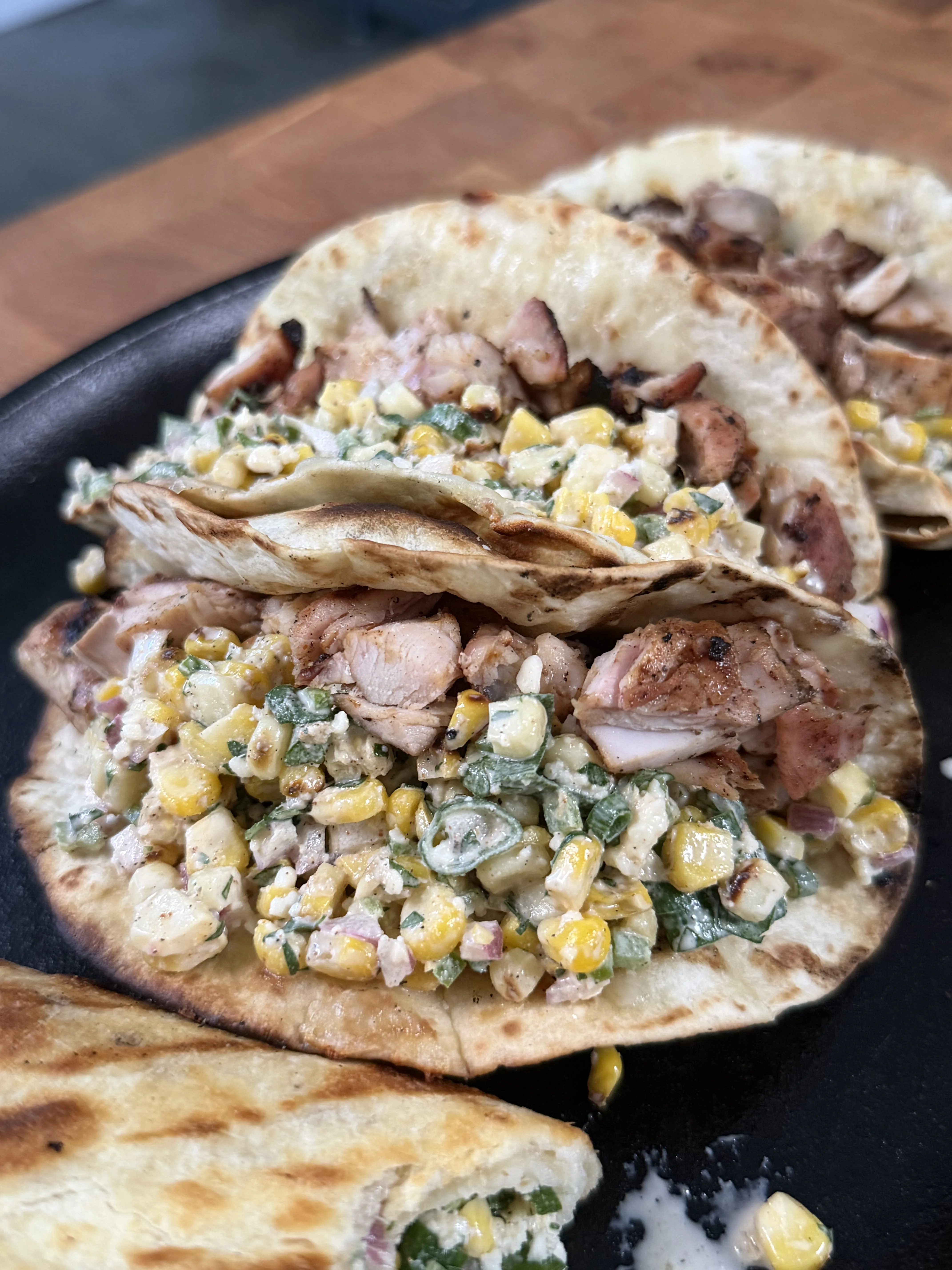 Grilled chicken elote tacos with corn topping and herbs served in a black cast iron skillet