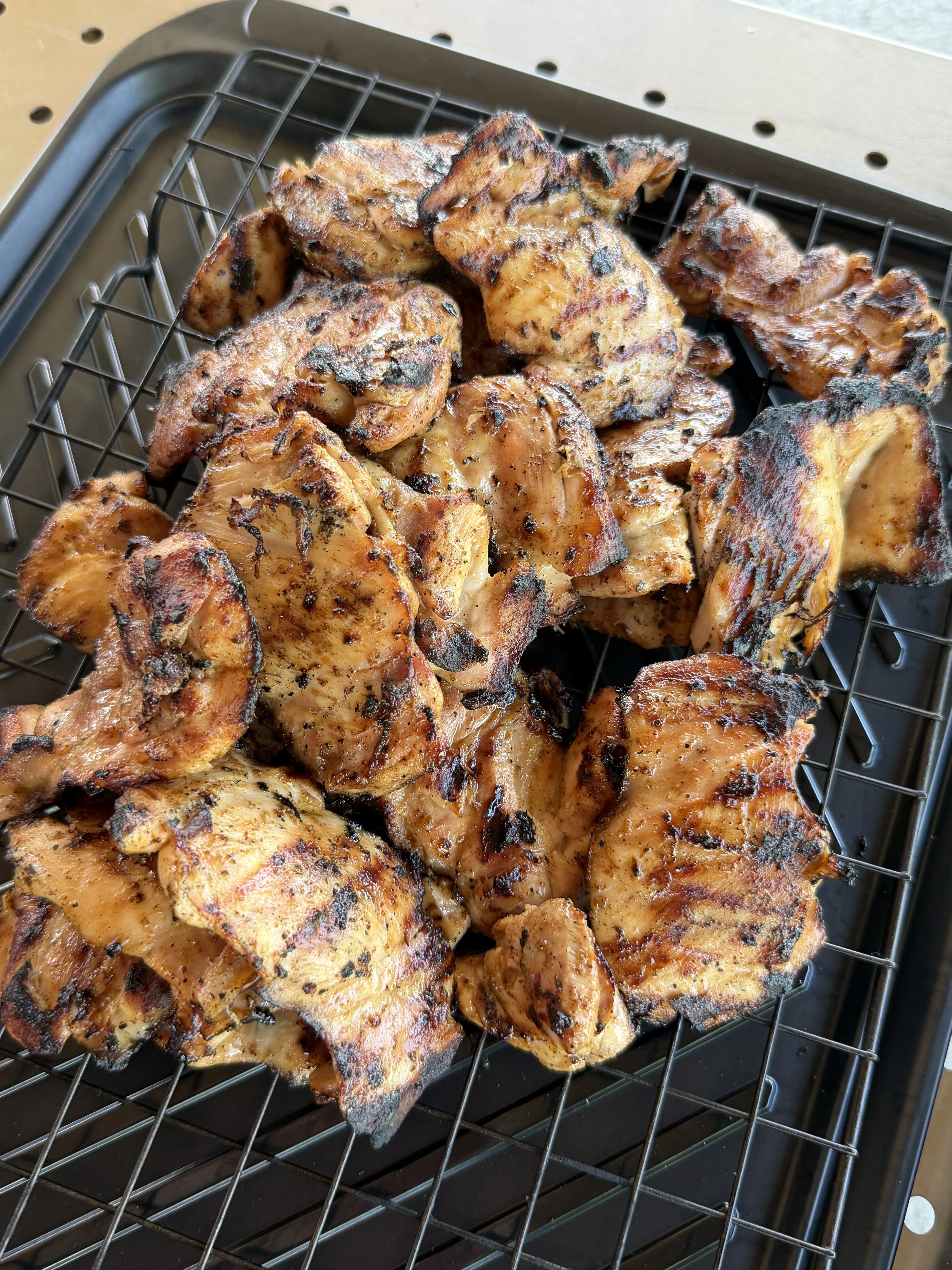Charred grilled chicken thighs with grill marks cooling on a wire rack