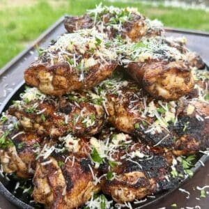 Grilled garlic Parmesan chicken thighs topped with grated Parmesan and fresh parsley in a cast iron skiller