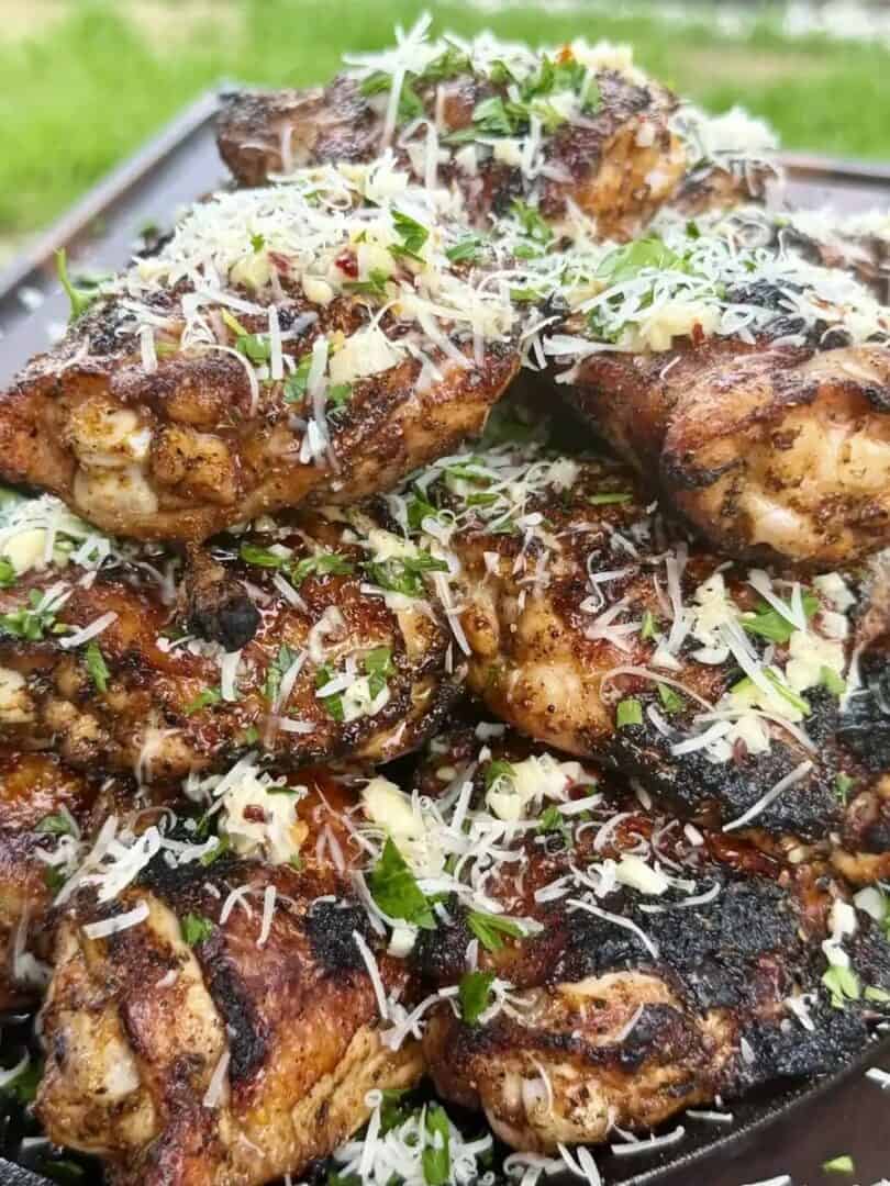 Grilled garlic Parmesan chicken thighs topped with grated Parmesan and fresh parsley in a cast iron skiller