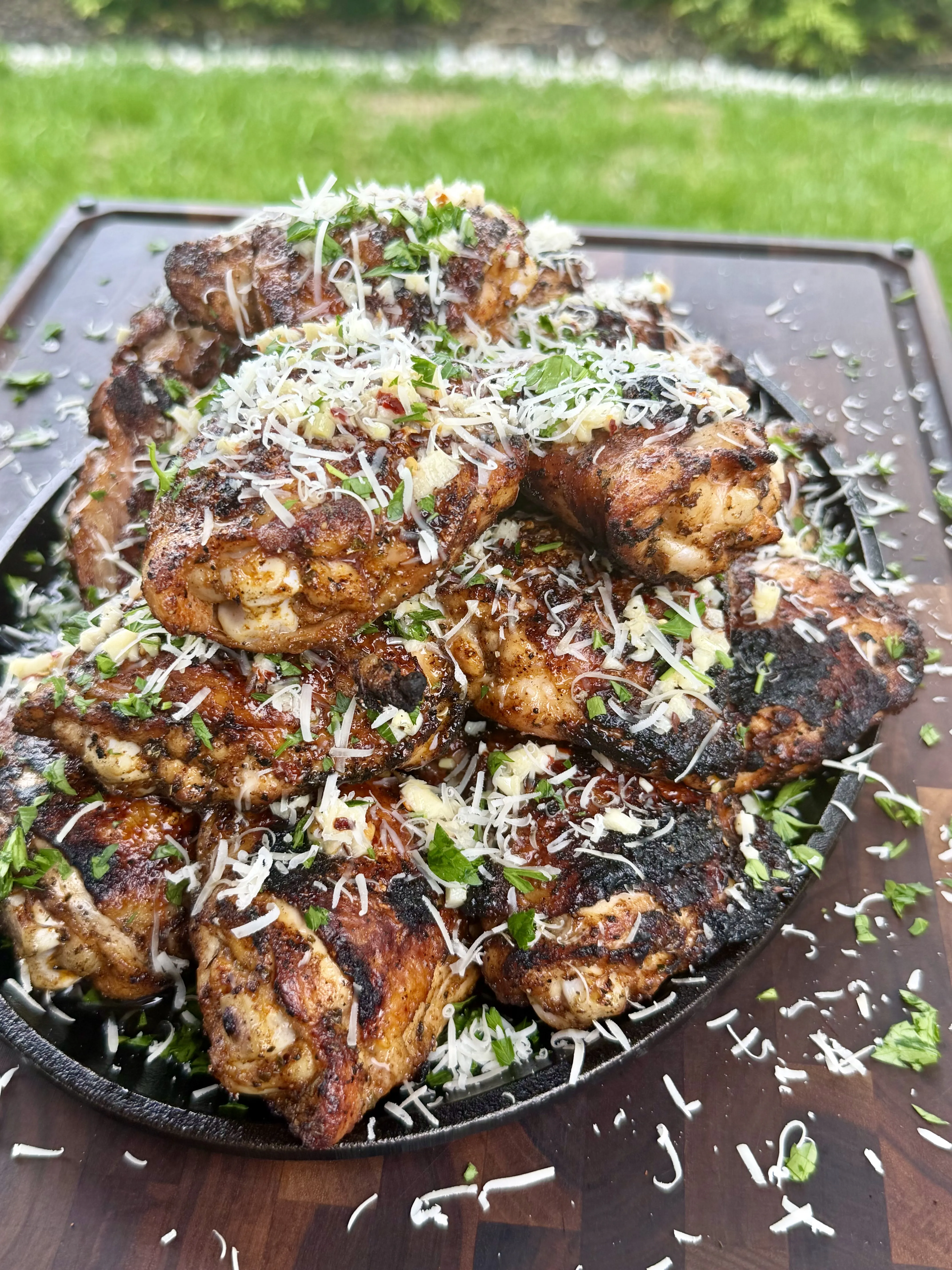 Crispy grilled garlic parmesan chicken thighs resting in a cast iron skillet