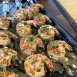 Grilled shrimp skewers with fresh herbs on a black serving tray, golden brown and ready to serve