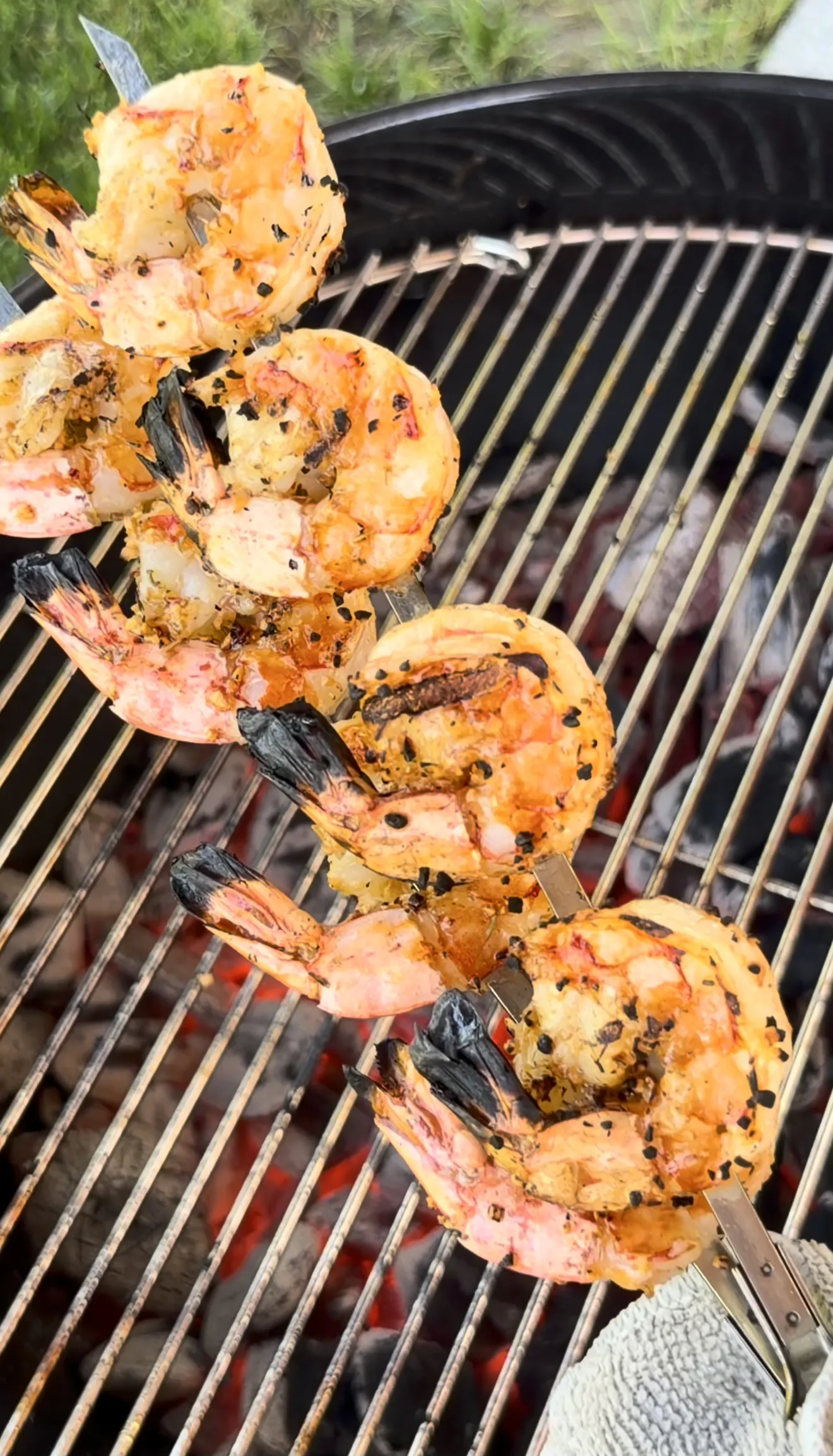 Roasted garlic herb grilled shrimp skewers cooking on barbecue grill with char marks