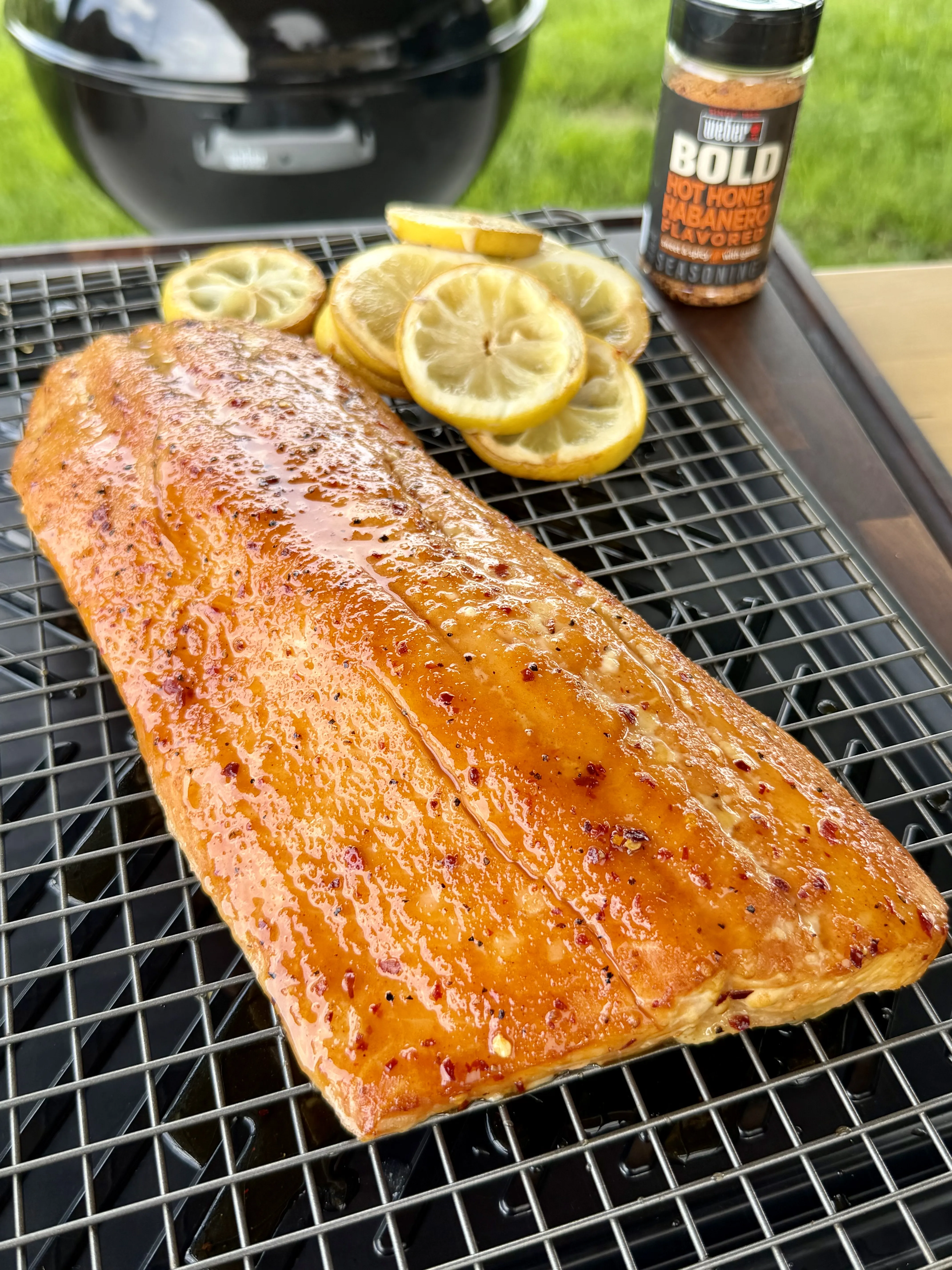 Finished hot honey glazed smoked salmon fillet on a wire cooling rack with lemon slices
