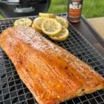 Hot honey glazed smoked salmon fillet on cooling rack with lemon slices and Weber BOLD seasoning bottle