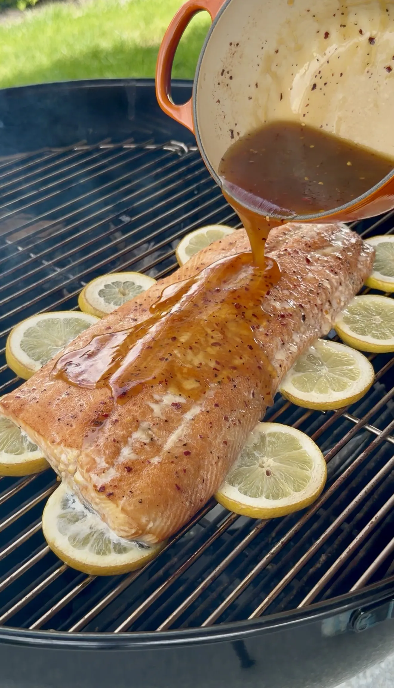 Finished hot honey glazed smoked salmon fillet on grill grates with lemon slices