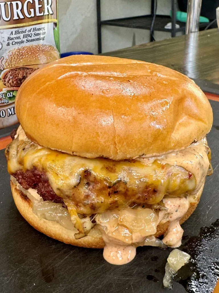 Juicy smoked Cajun burger with melted cheese and sauce on golden brioche bun