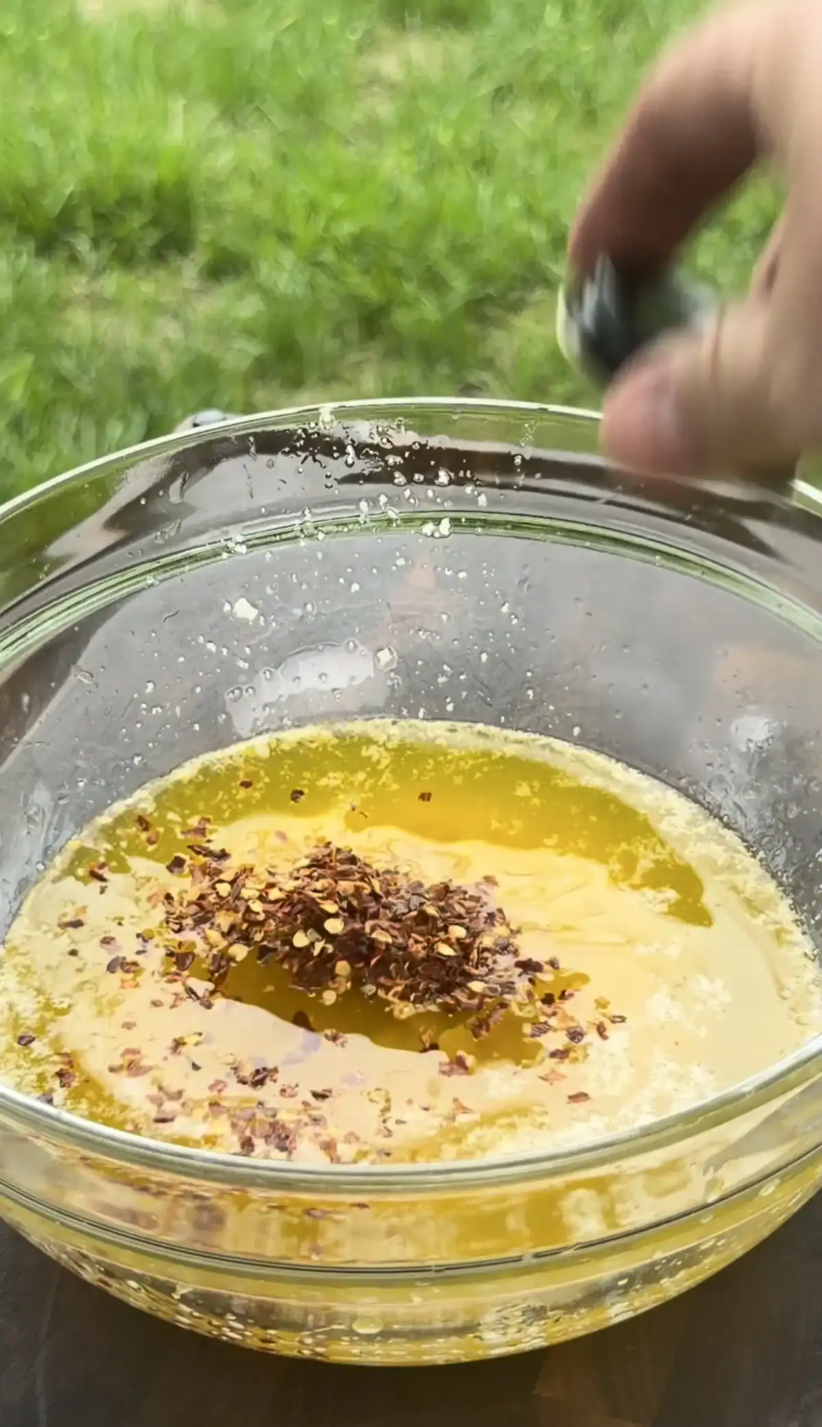 Melted butter and red pepper flakes in a glass bowl for garlic Parmesan sauce.