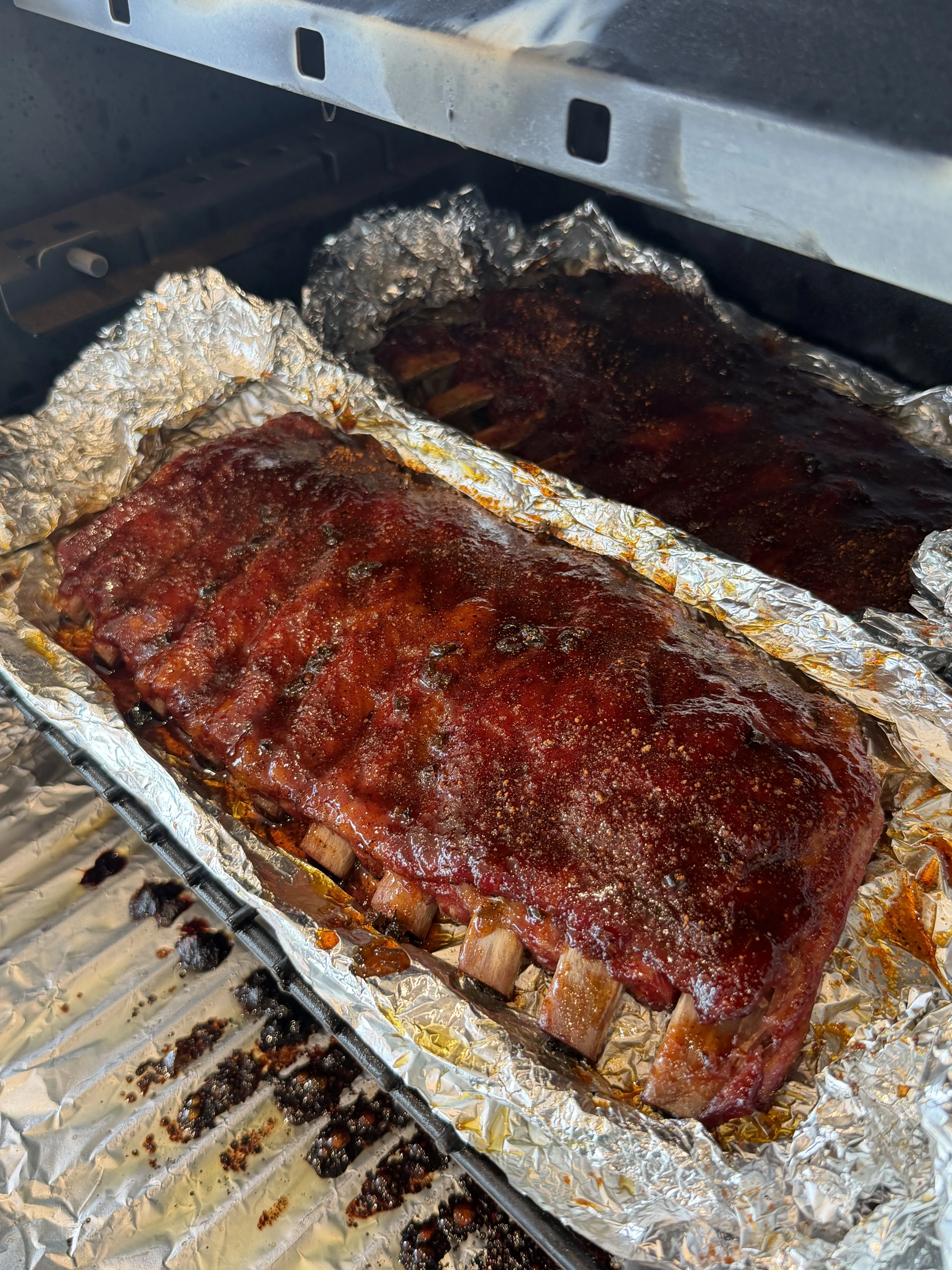 Pellet smoked ribs wrapped in foil on the grill during the wrap phase