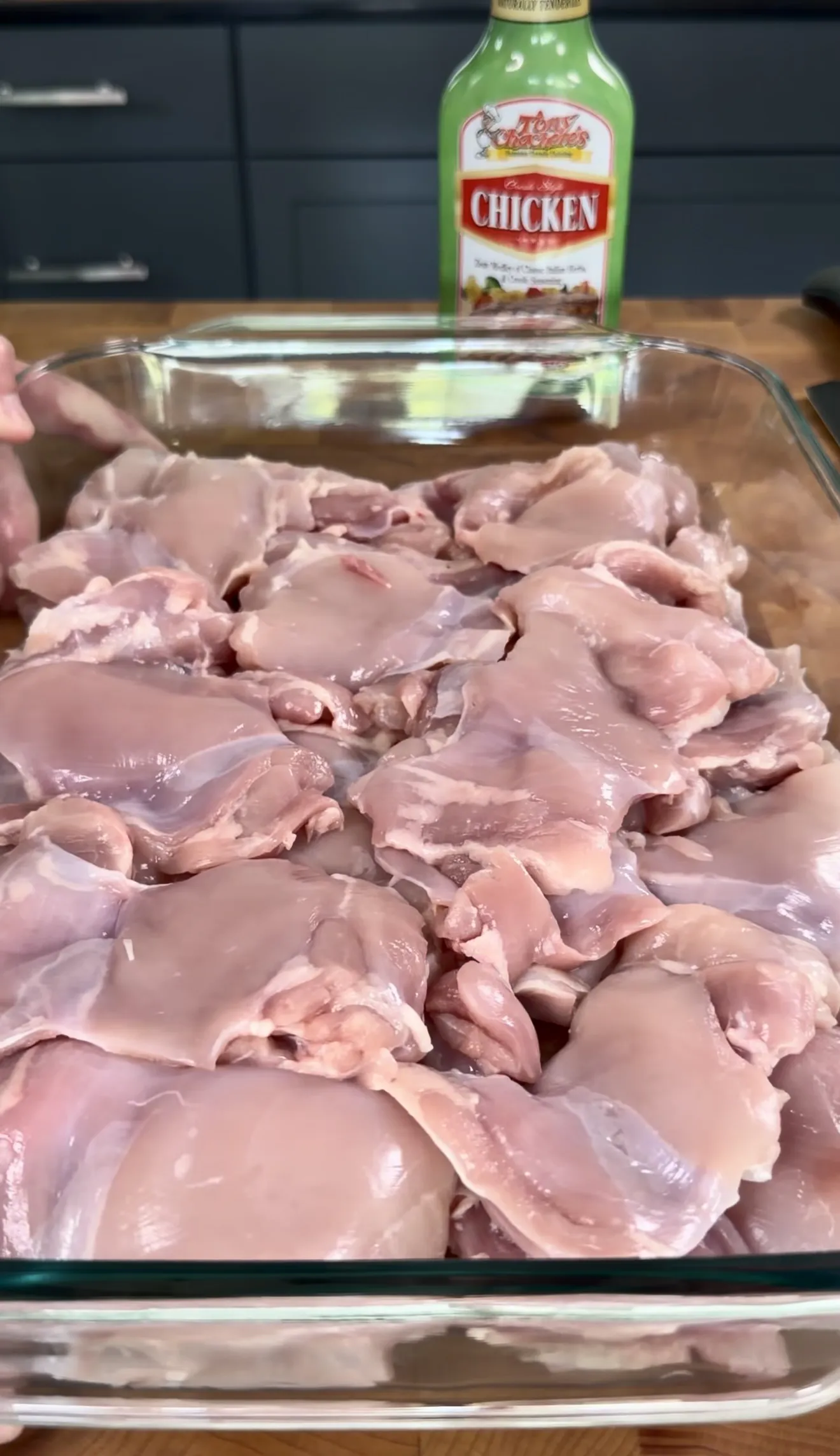 Raw boneless skinless chicken thighs marinating in a glass baking dish