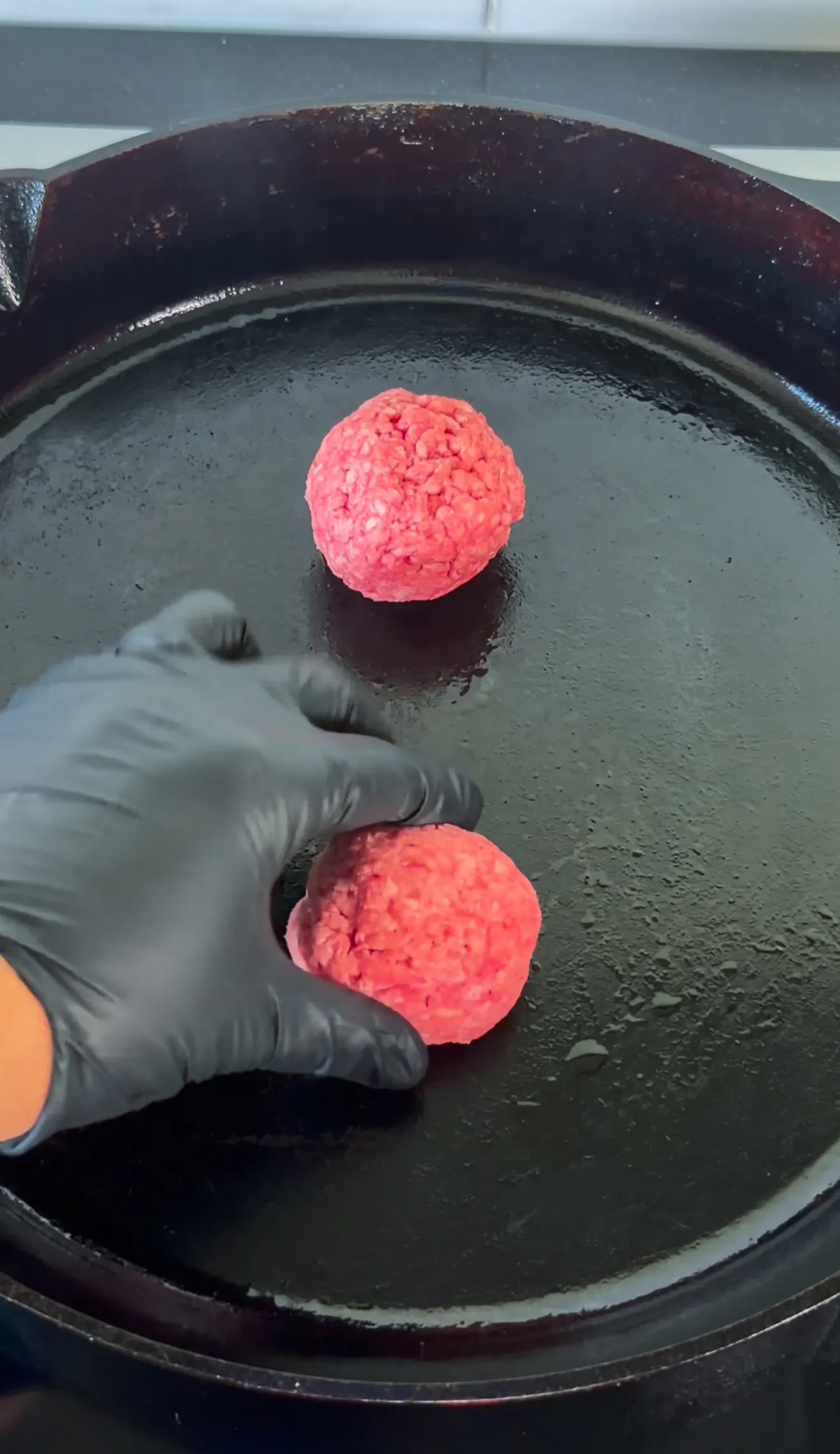 Raw ground beef patties being formed by hand in a pan for bacon jam smash burgers