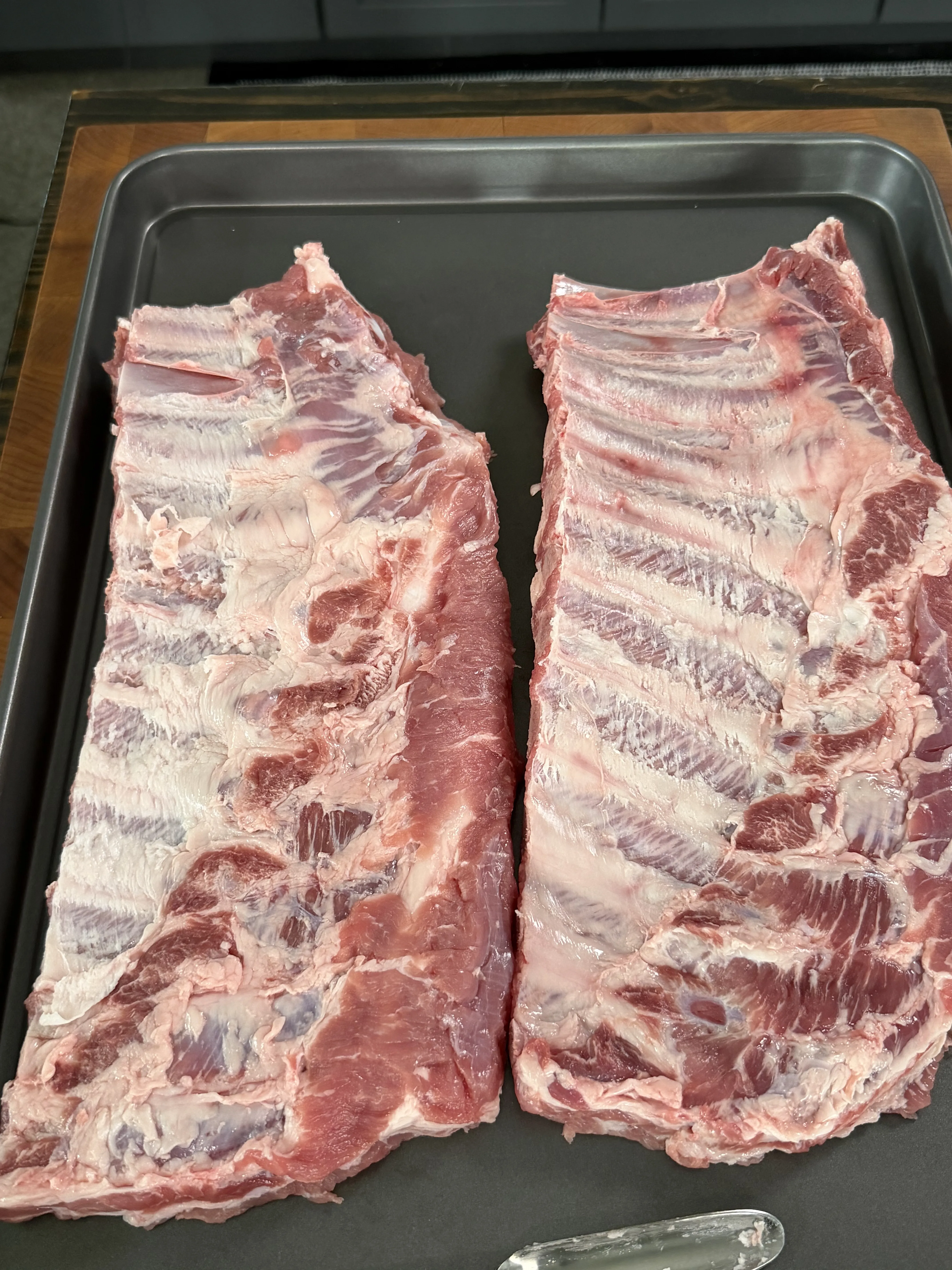 Raw pork ribs in a metal pan ready for smoking preparation
