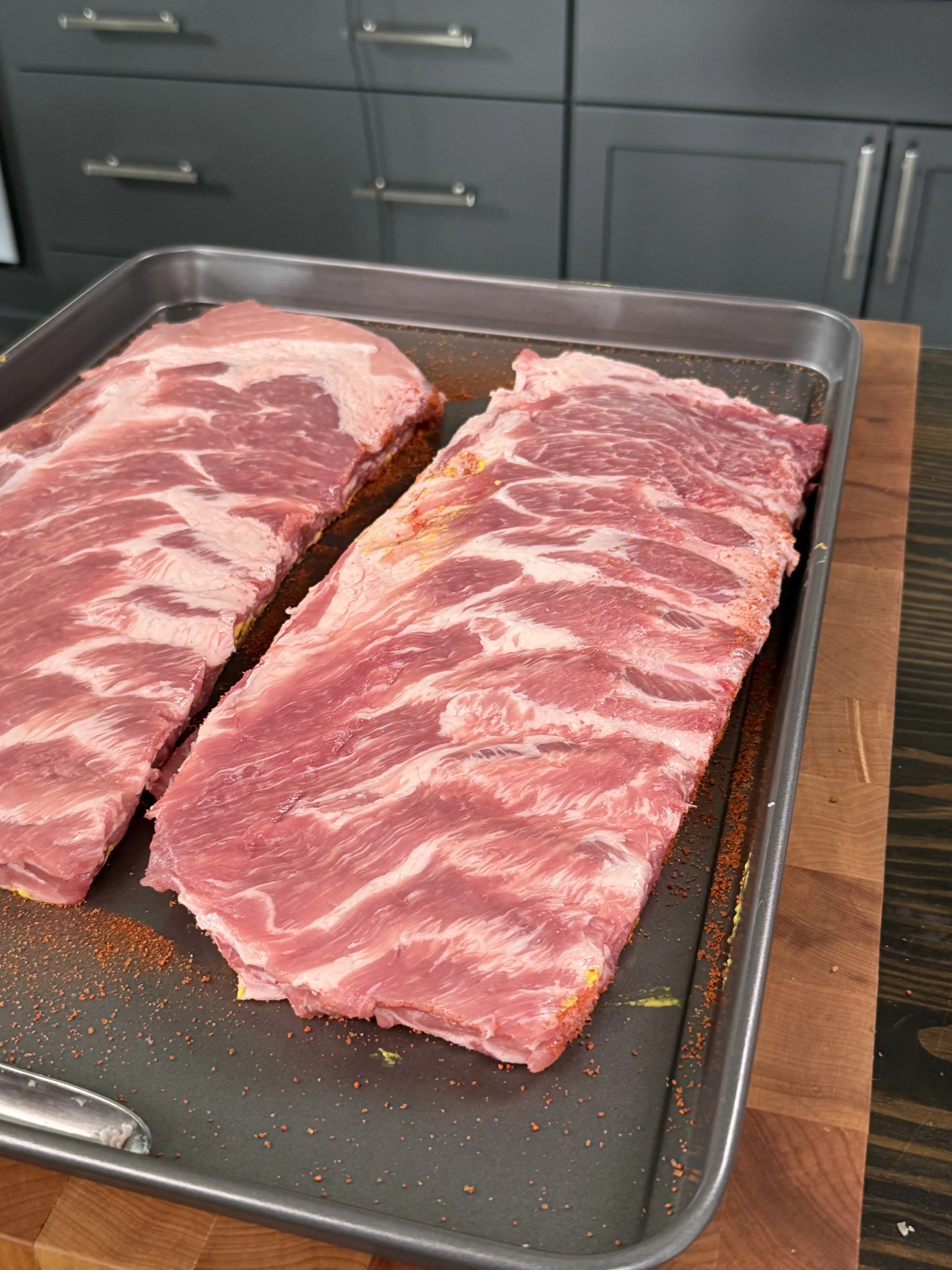 Raw pork ribs seasoned with rub on a baking sheet