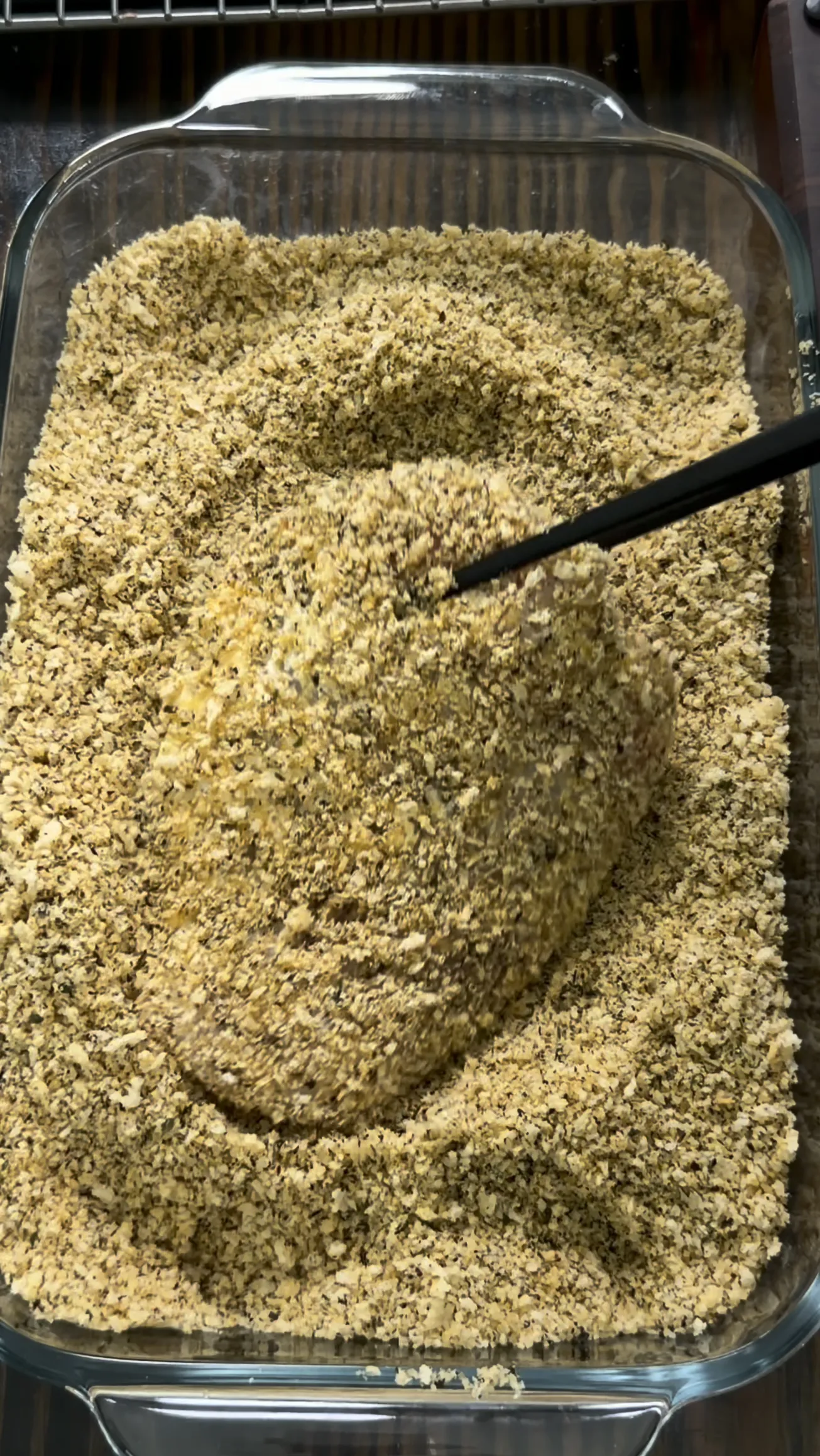 Seasoned breadcrumb mixture in a glass baking dish for chicken cutlets