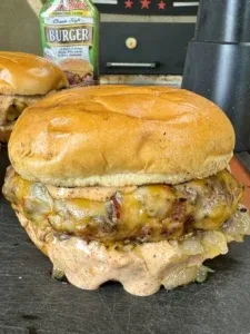 Finished smoked Cajun burger with melted cheese and caramelized onions on a toasted brioche bun