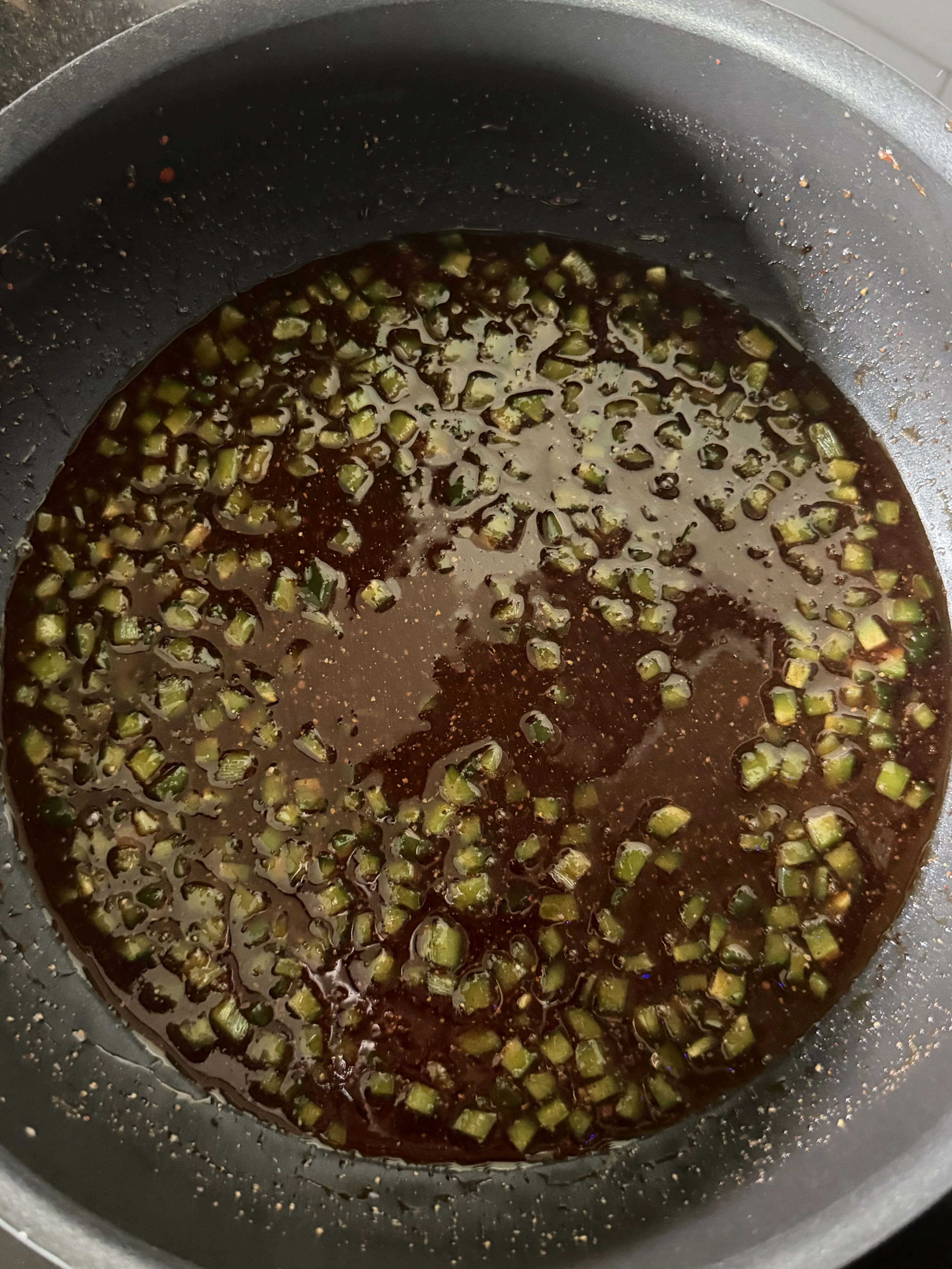 Honey jalapeño BBQ sauce with green onions simmering in a pan