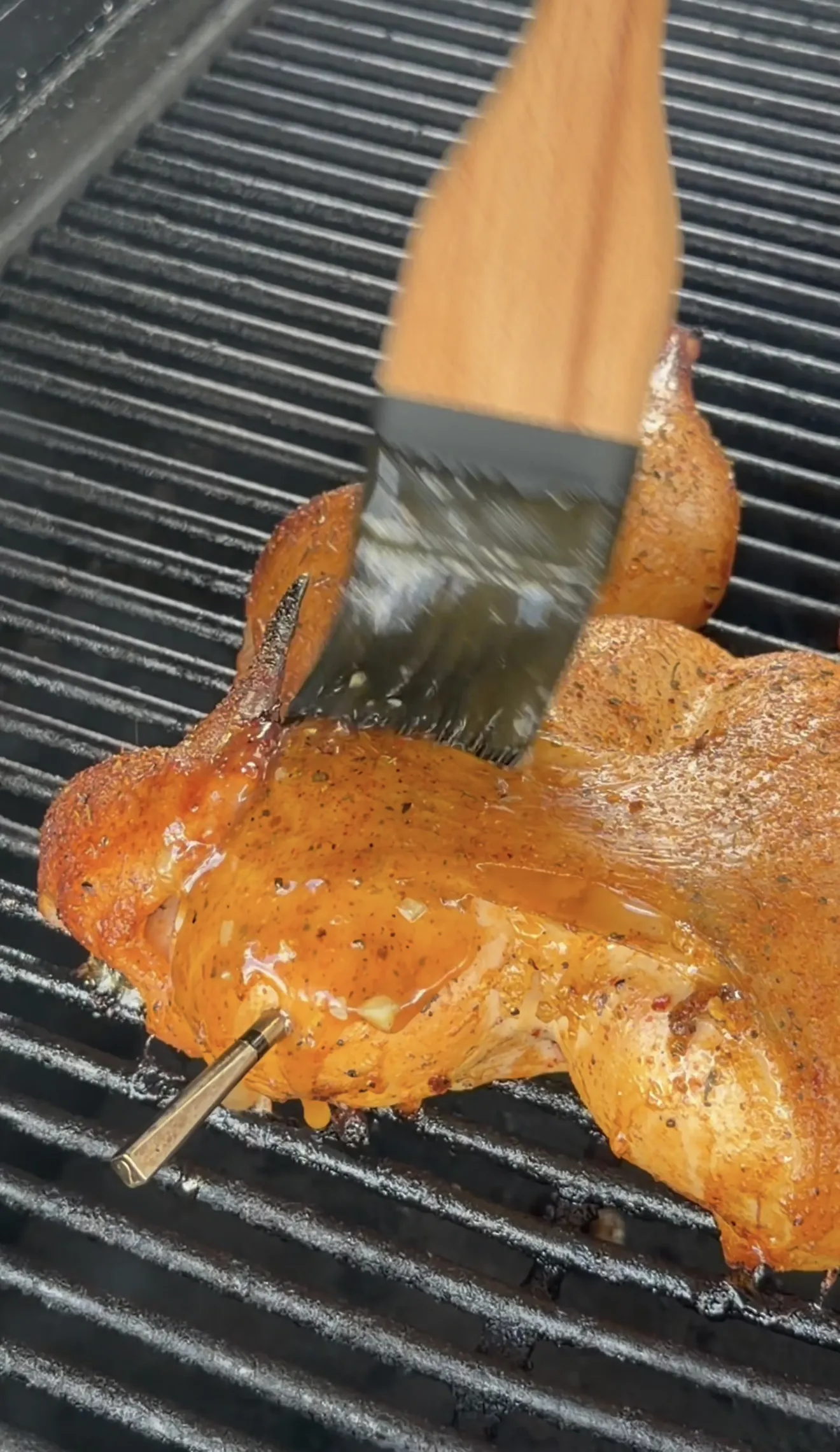 Spatchcock chicken being basted with herb butter while grilling