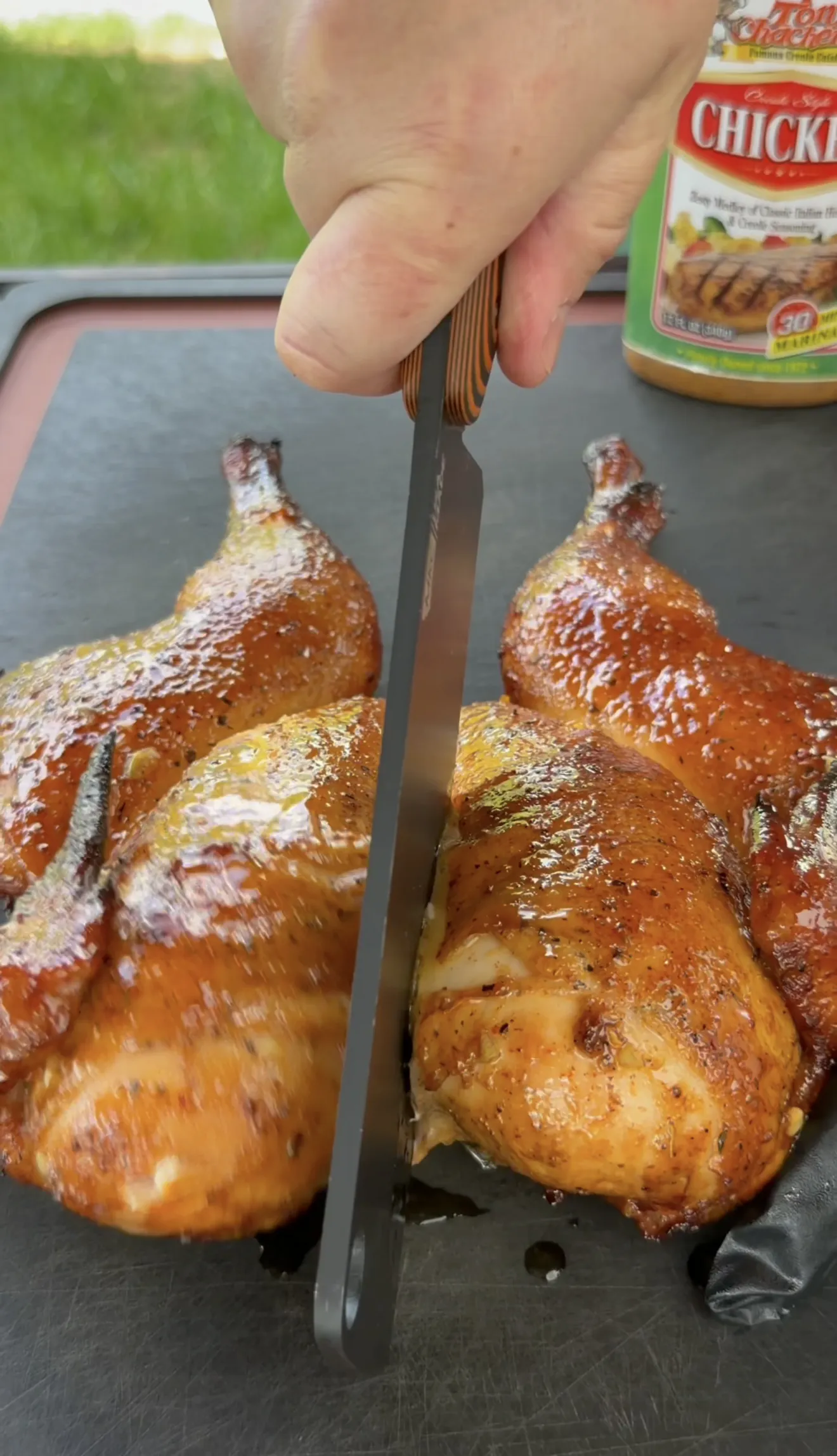 Spatchcock chicken being carved with a knife on a cutting board