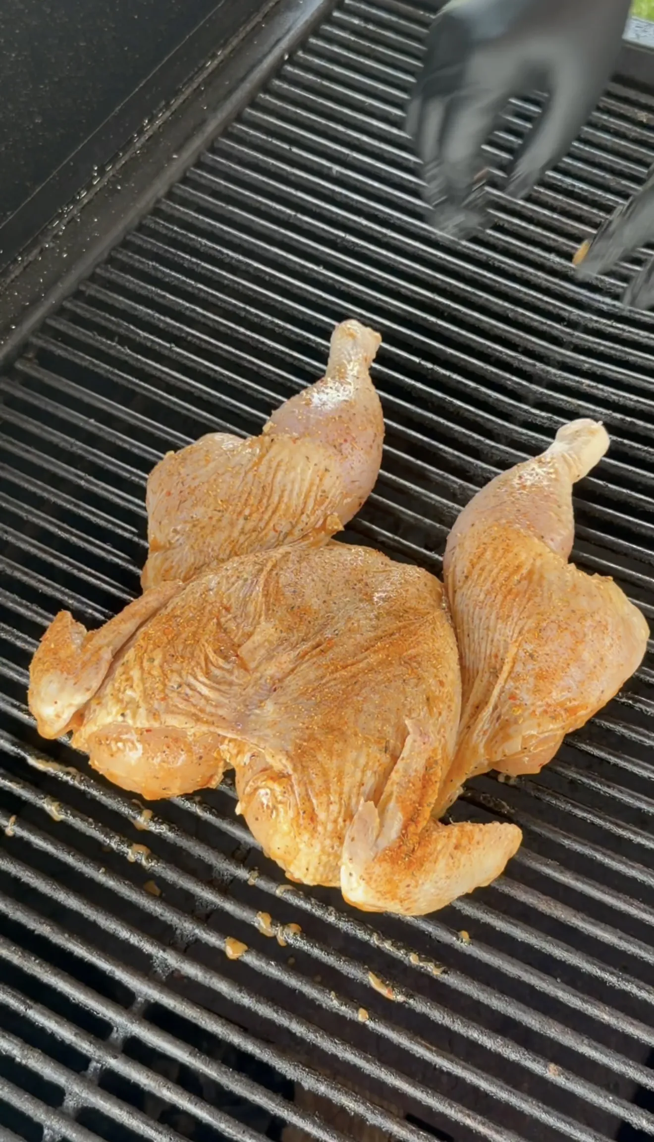 Spatchcock chicken cooking skin-side up on grill grates at 275 degrees