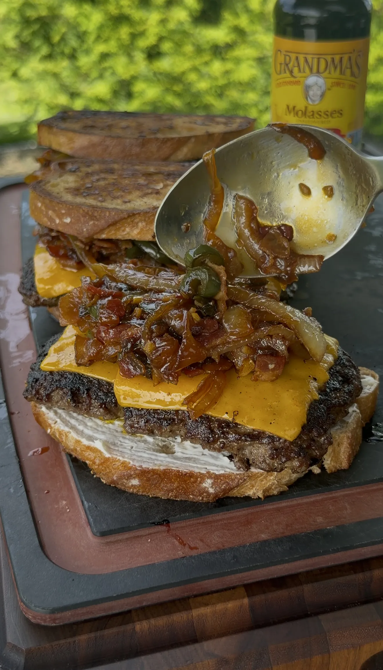 Bacon jam patty melt being assembled with caramelized onions and melted cheese