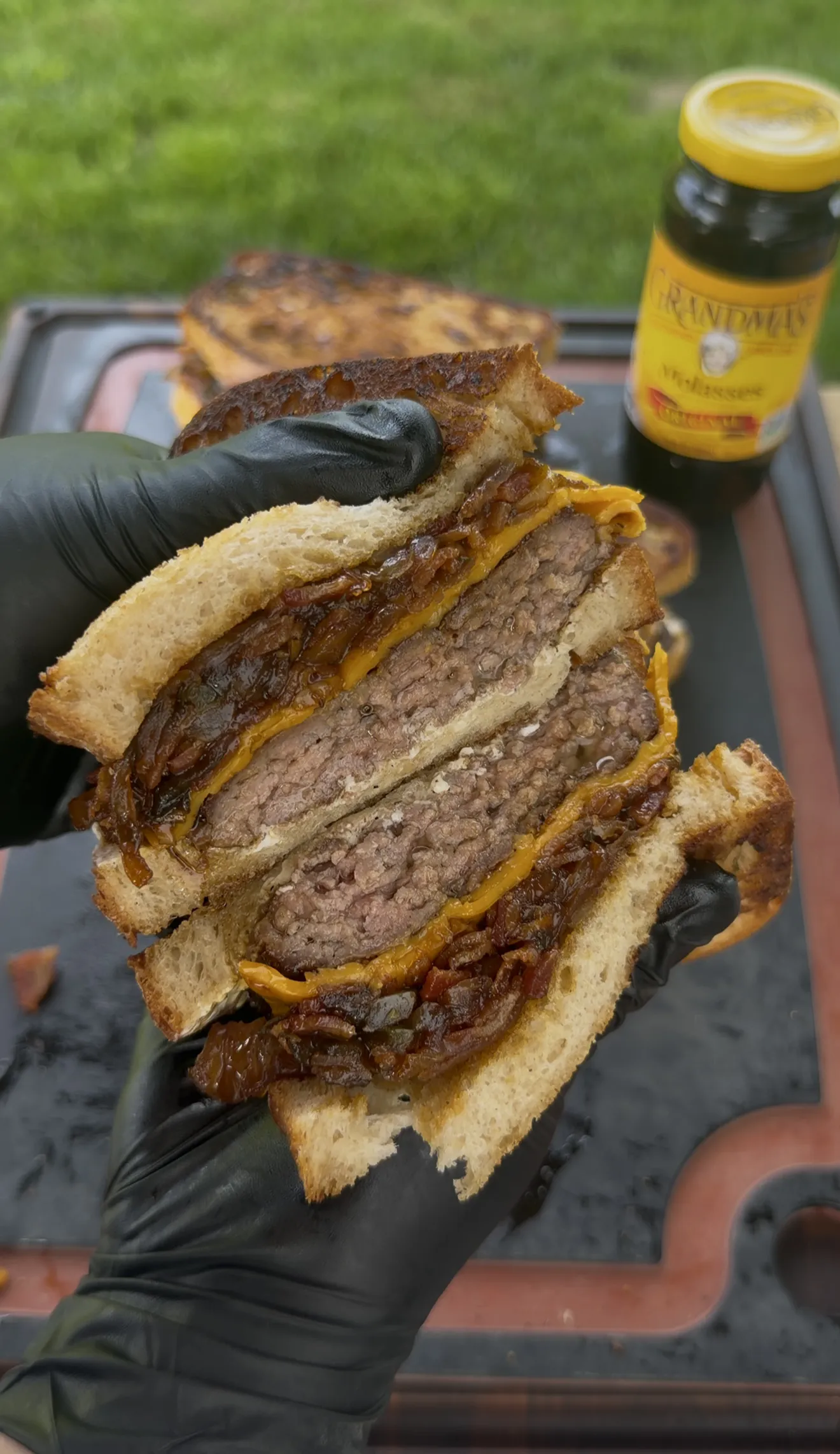 Cross-section of bacon jam patty melt showing beef patty, melted cheese, and caramelized onions on grilled sourdough