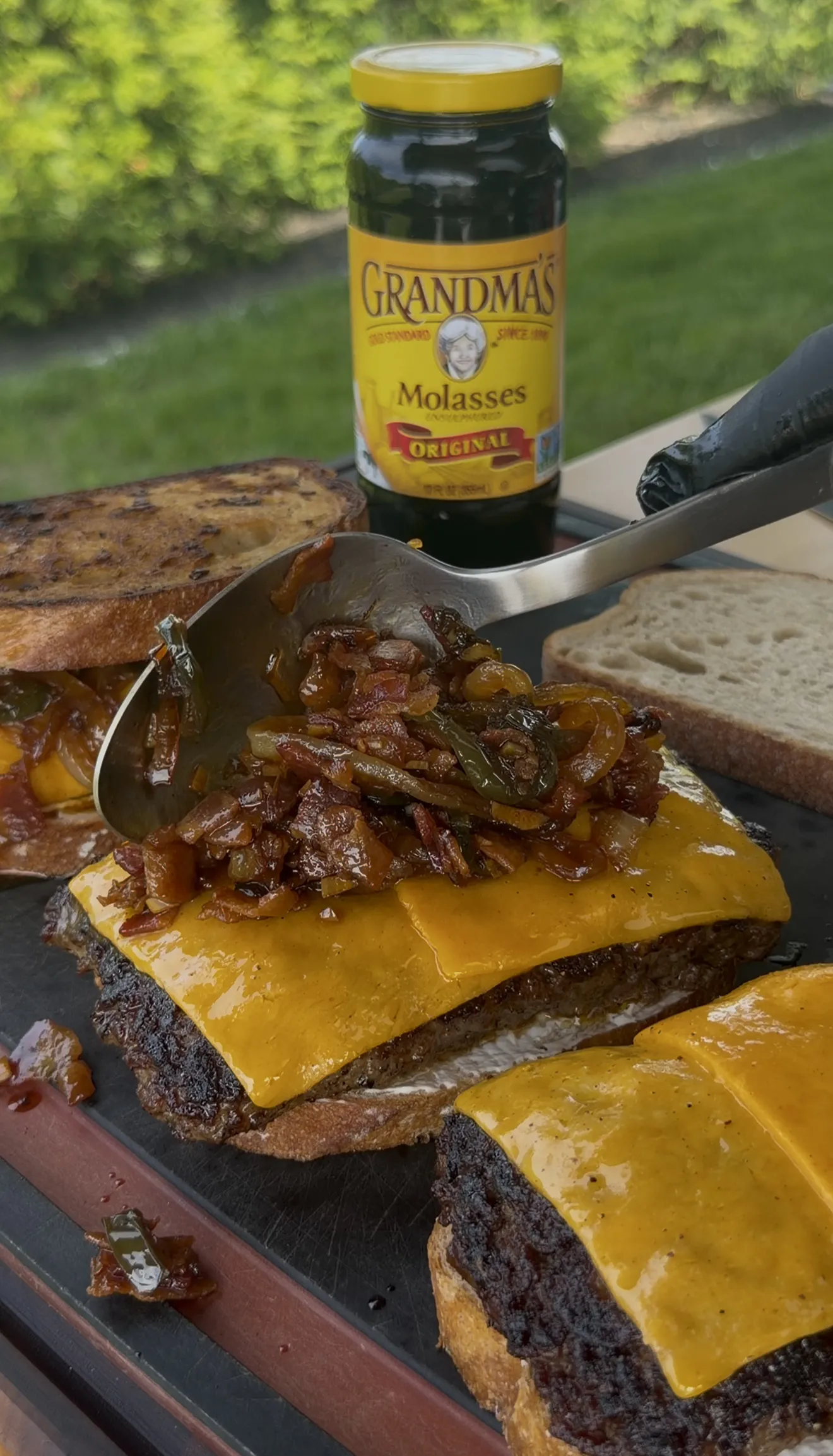 Finished bacon jam patty melts with melted cheese on grilled sourdough served on a wooden board