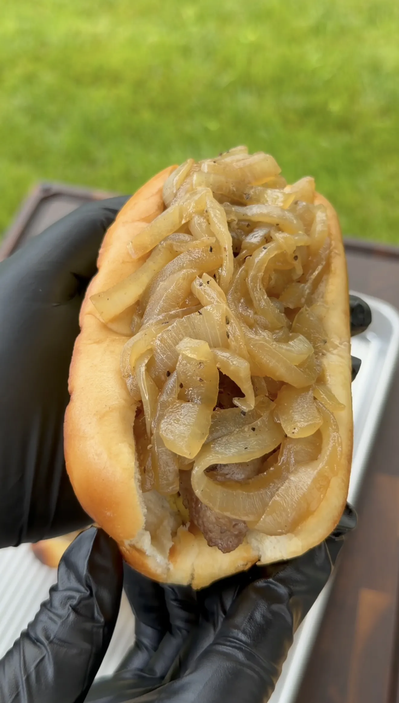Beer brat on a hoagie bun piled high with golden caramelized onions