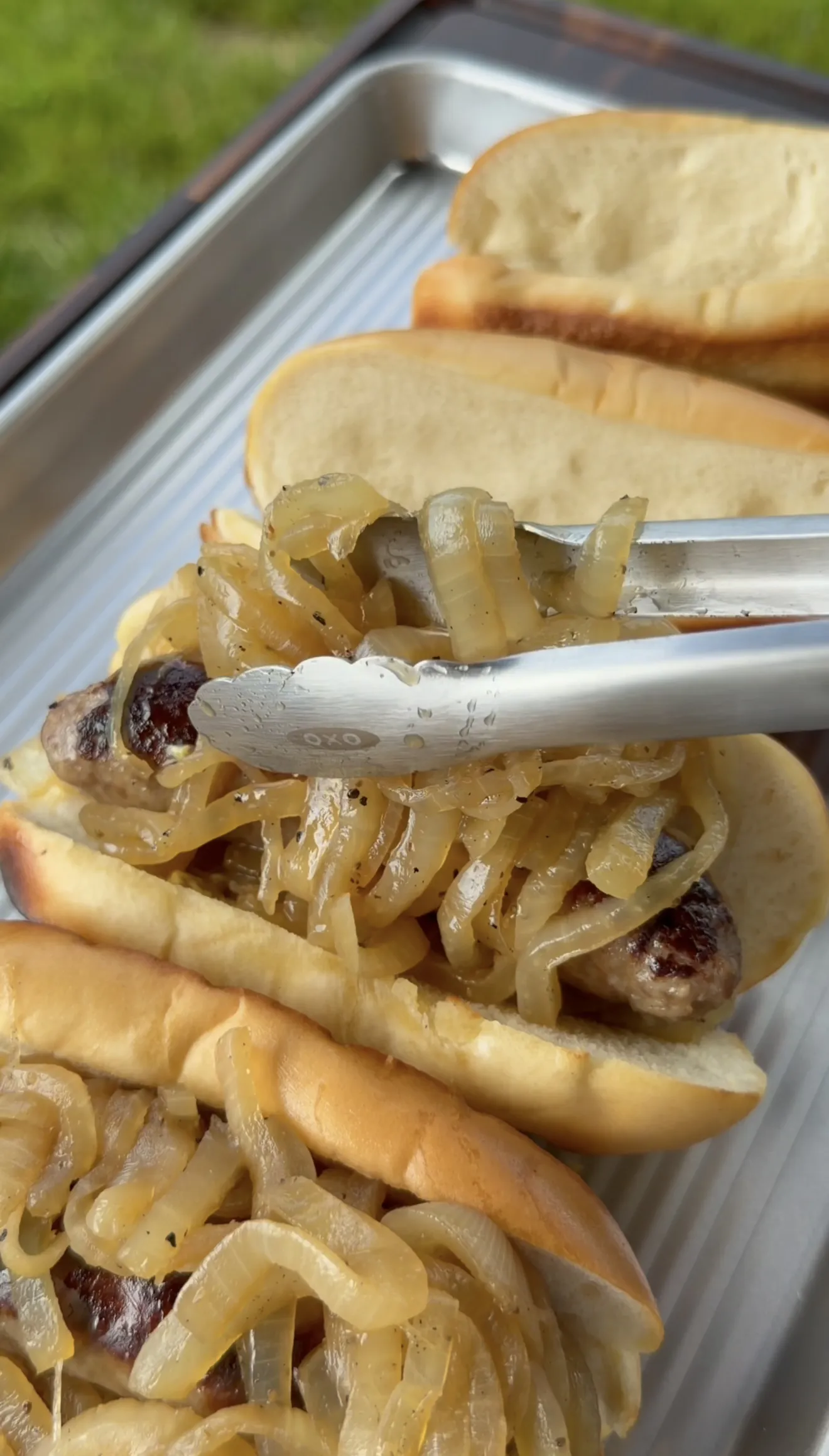 Beer brats topped with caramelized onions in toasted hoagie buns ready to serve