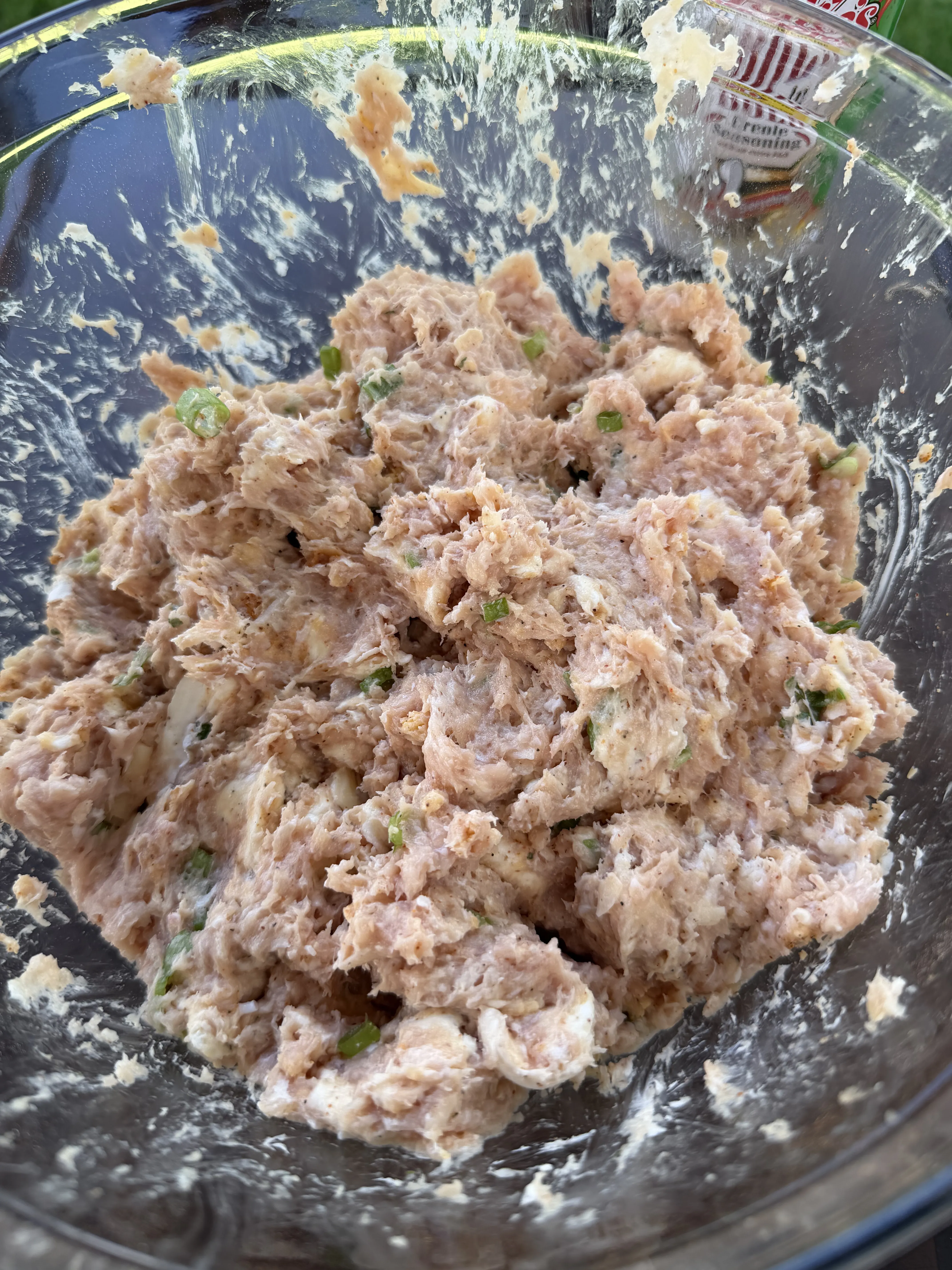 Creamy buffalo chicken filling with cheese and scallions mixed in a glass bowl