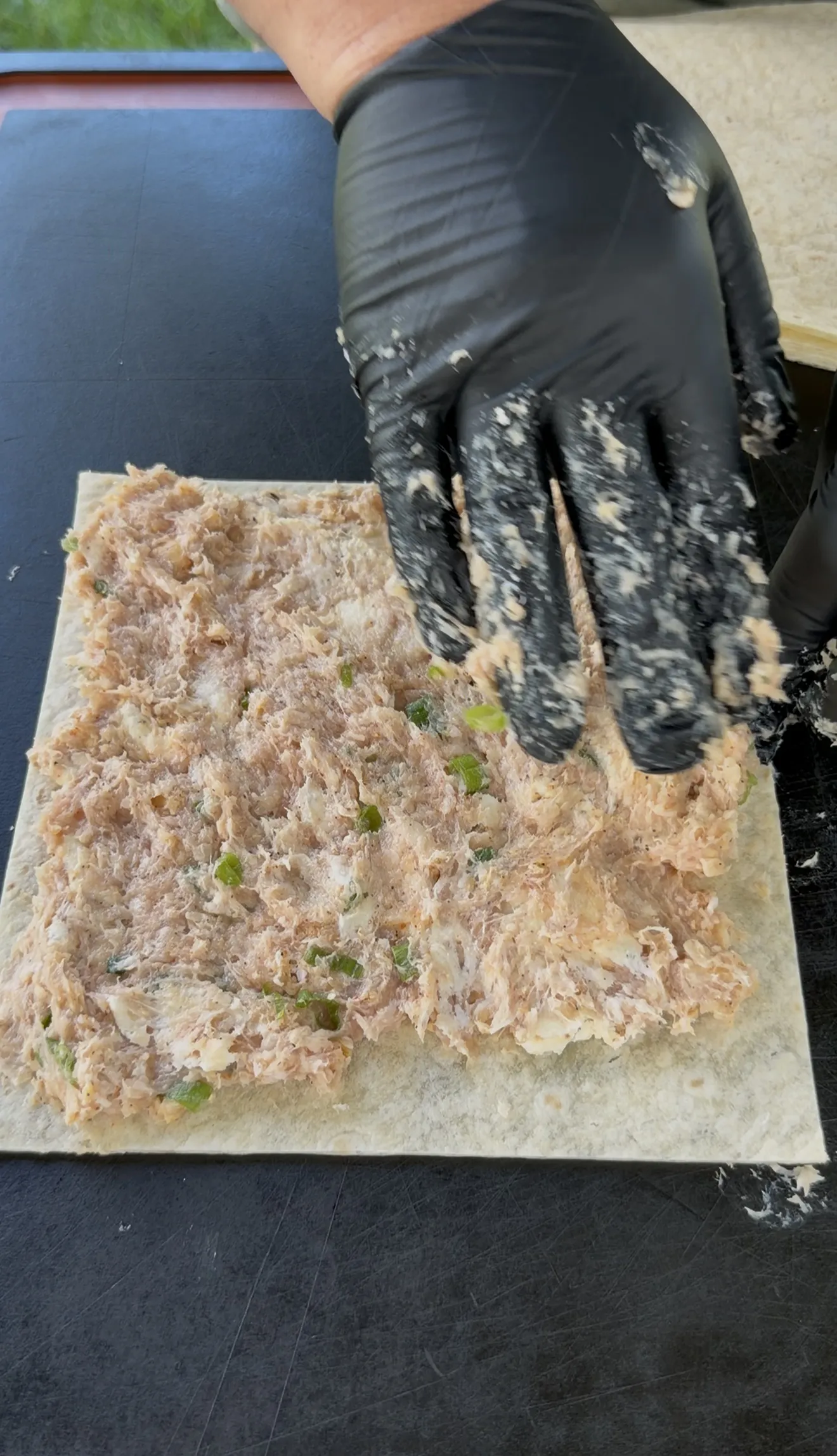 Buffalo chicken filling spread in a thin even layer across a flour tortilla