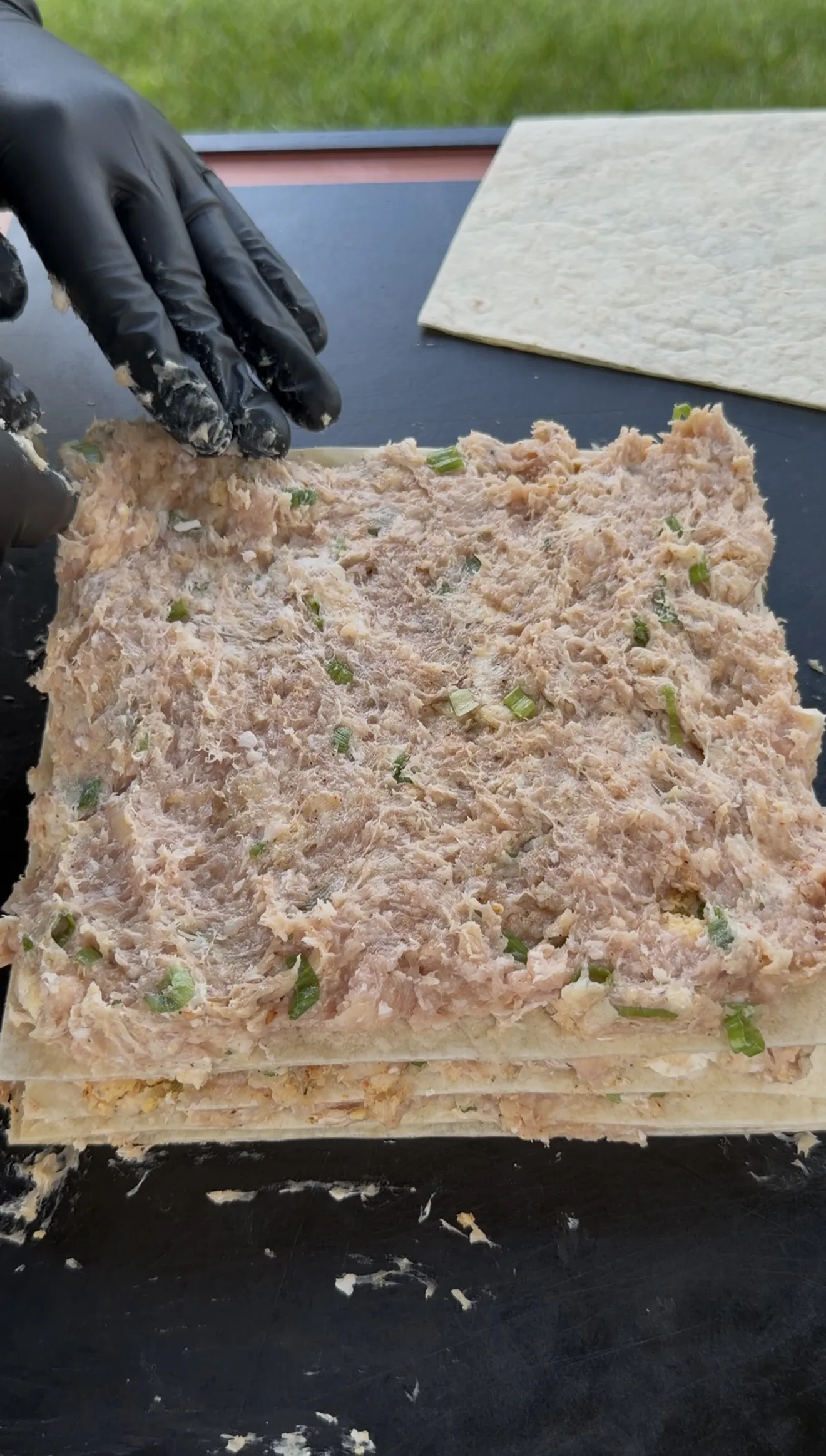 Creamy buffalo chicken mixture spread on a large burrito-size flour tortilla