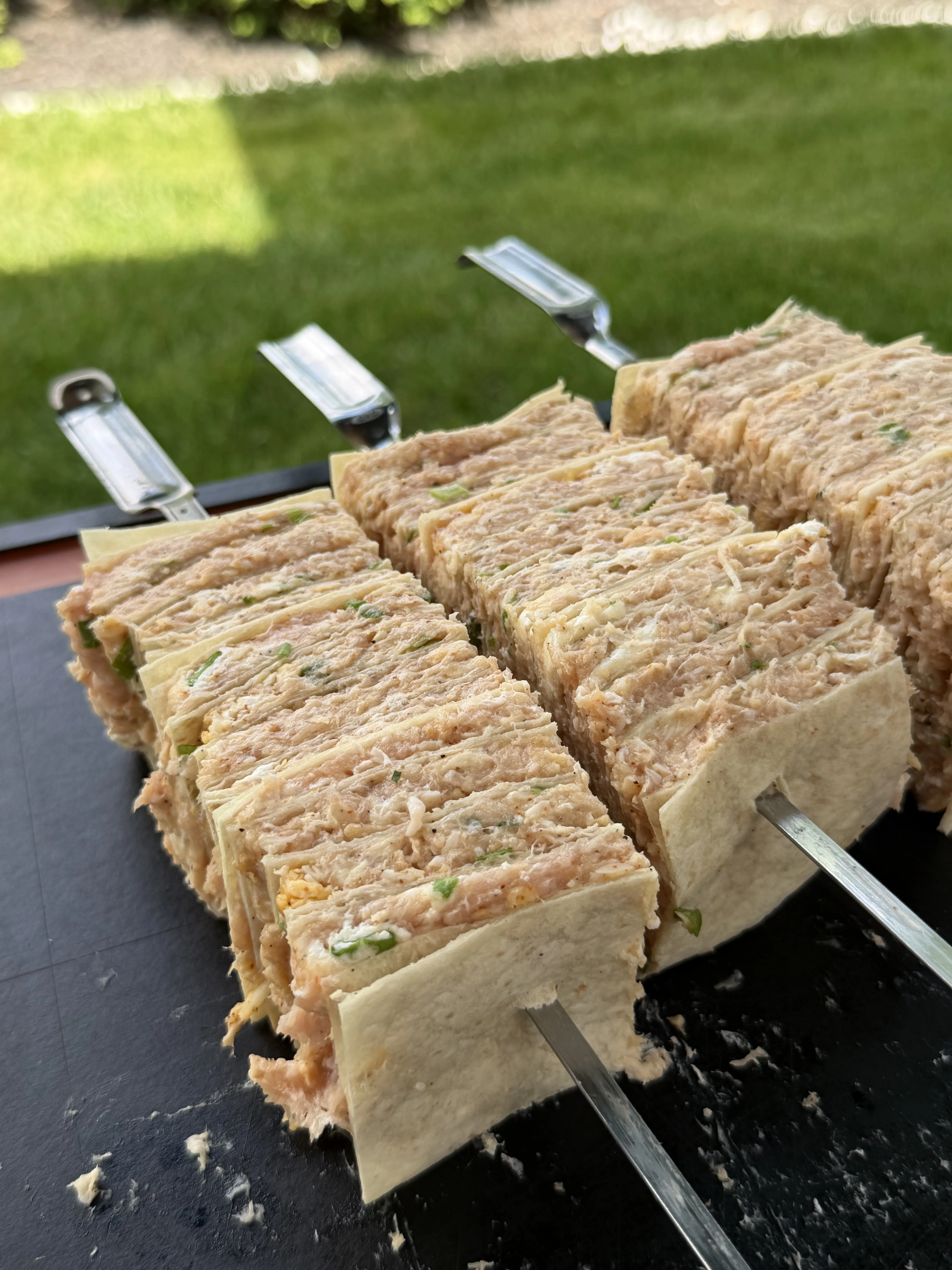 Buffalo chicken tortilla kebabs sliced and skewered on a cutting board