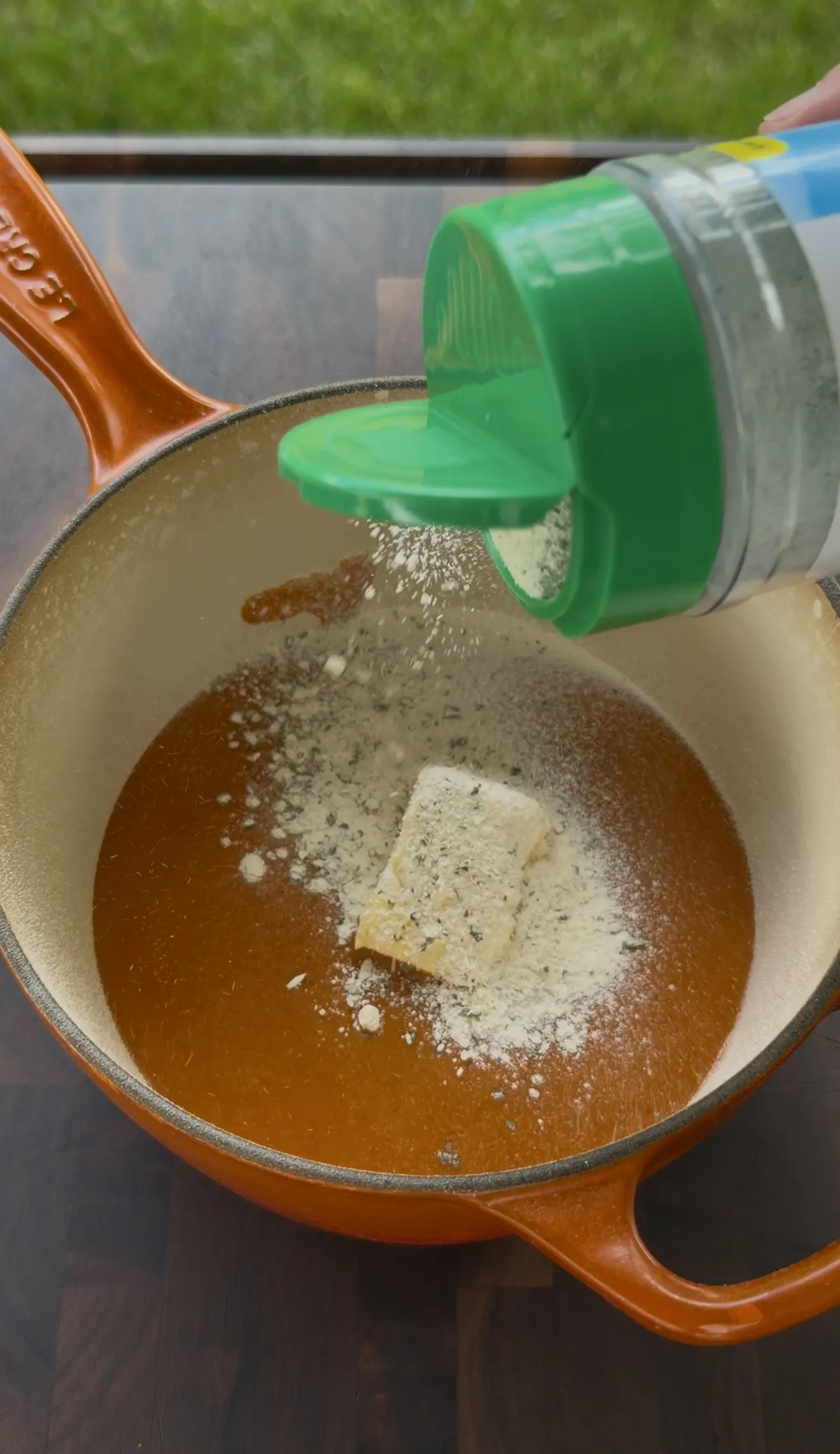 Butter and Creole seasoning melting together for buffalo butter in an orange pot
