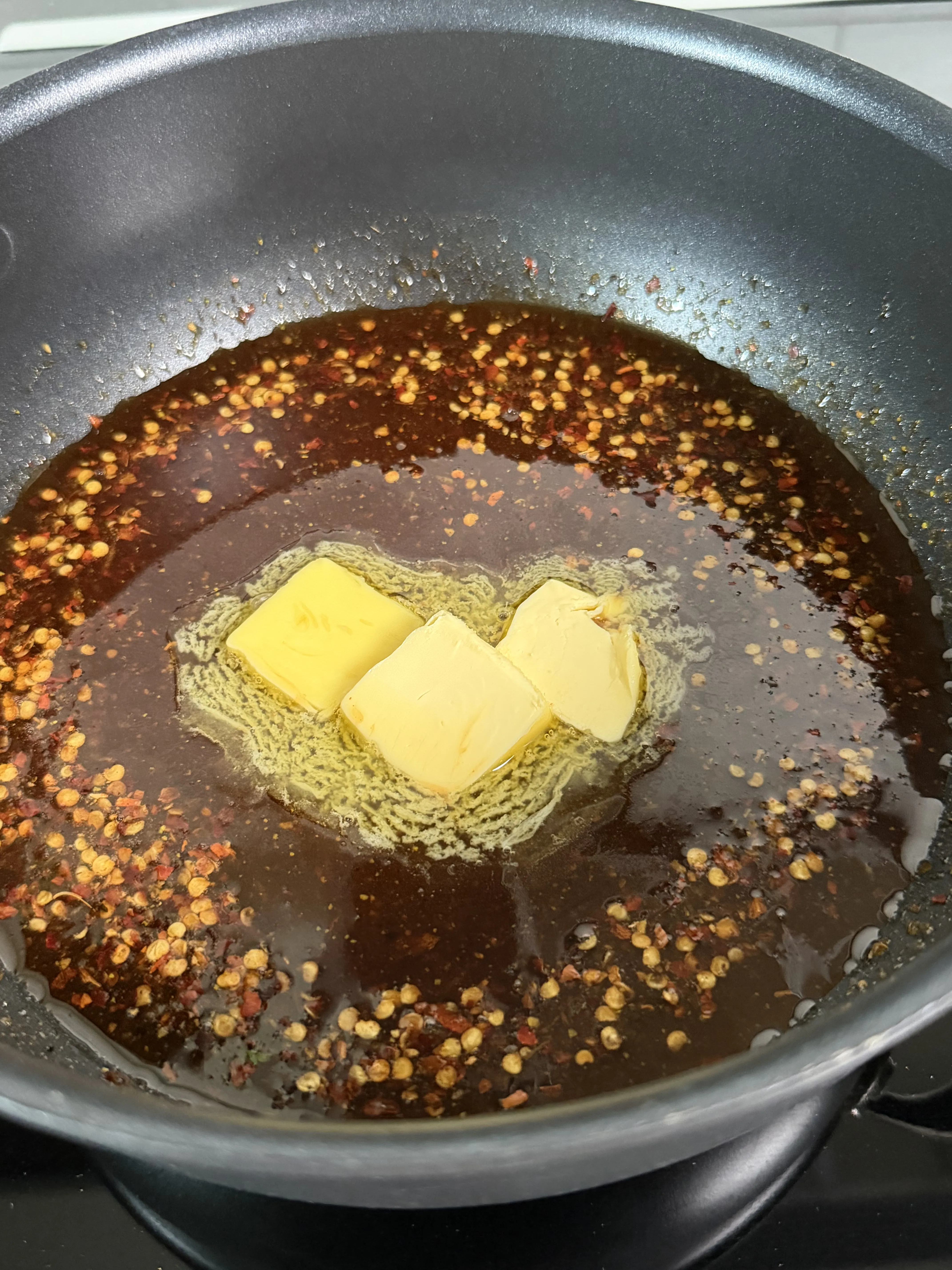 Hot honey lemon pepper sauce coming together over low heat in a dark pan