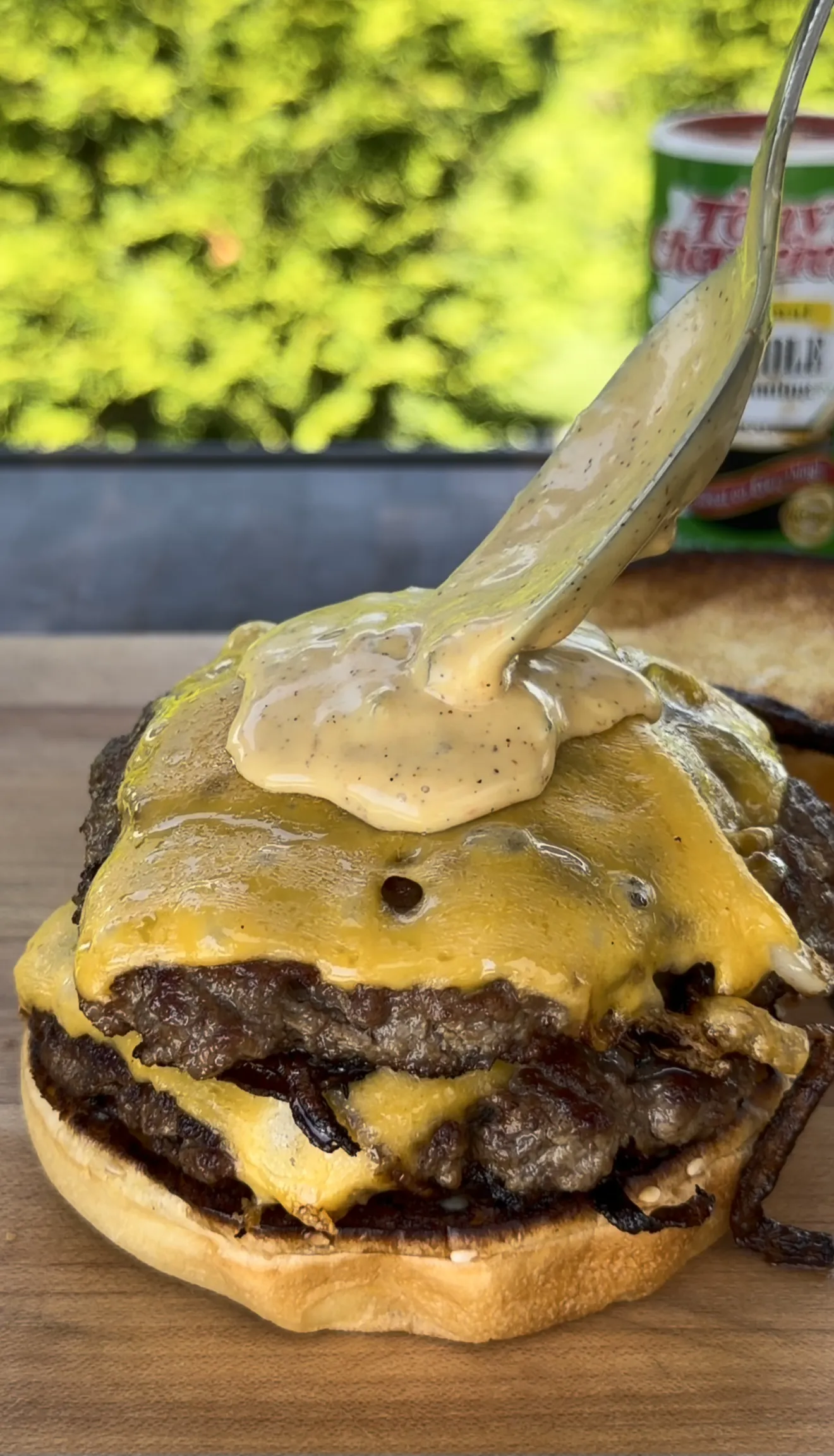 Cajun Oklahoma onion smash burger being built with cheese and Cajun sauce