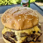 Cajun Oklahoma onion smash burger with melted cheese on sesame bun, Tony Chachere's Creole seasoning in background