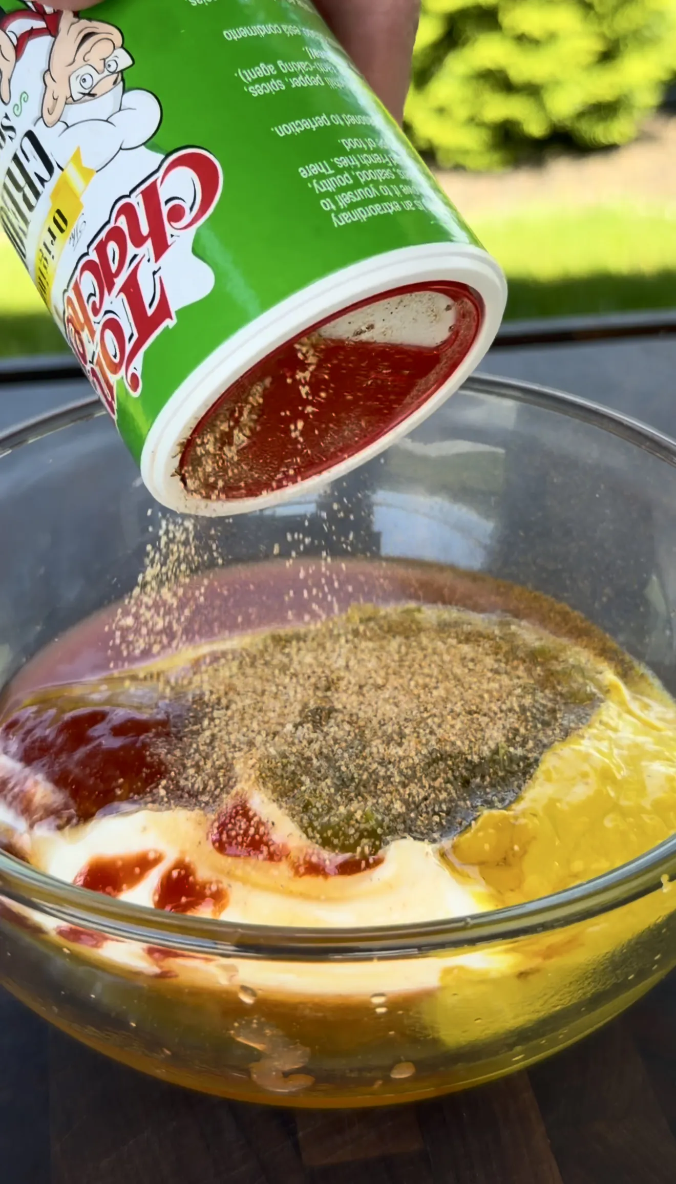 Tony's Creole Seasoning being added to the Cajun burger sauce