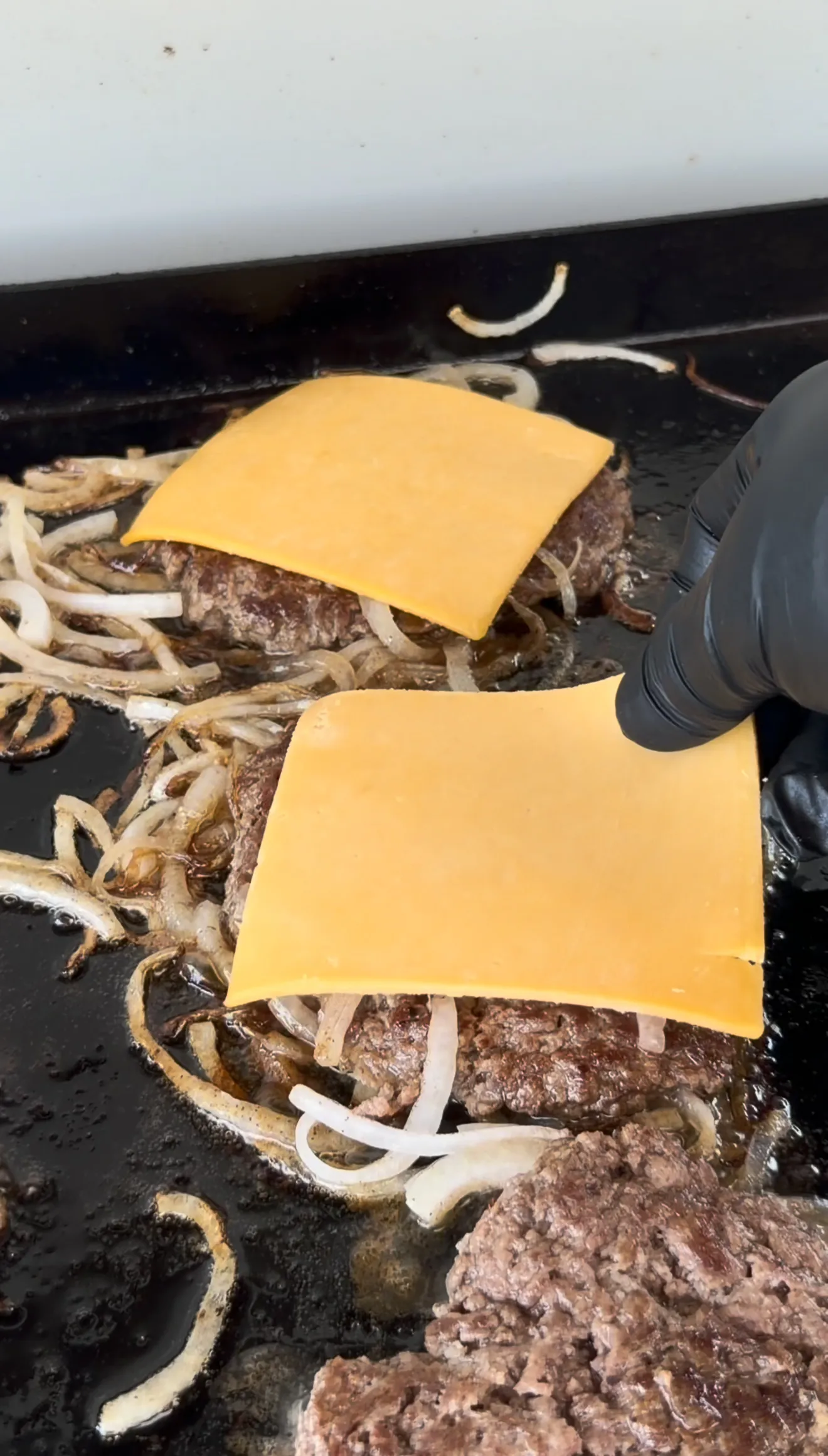 Cajun smash burgers with melted American cheese and caramelized onions on the griddle
