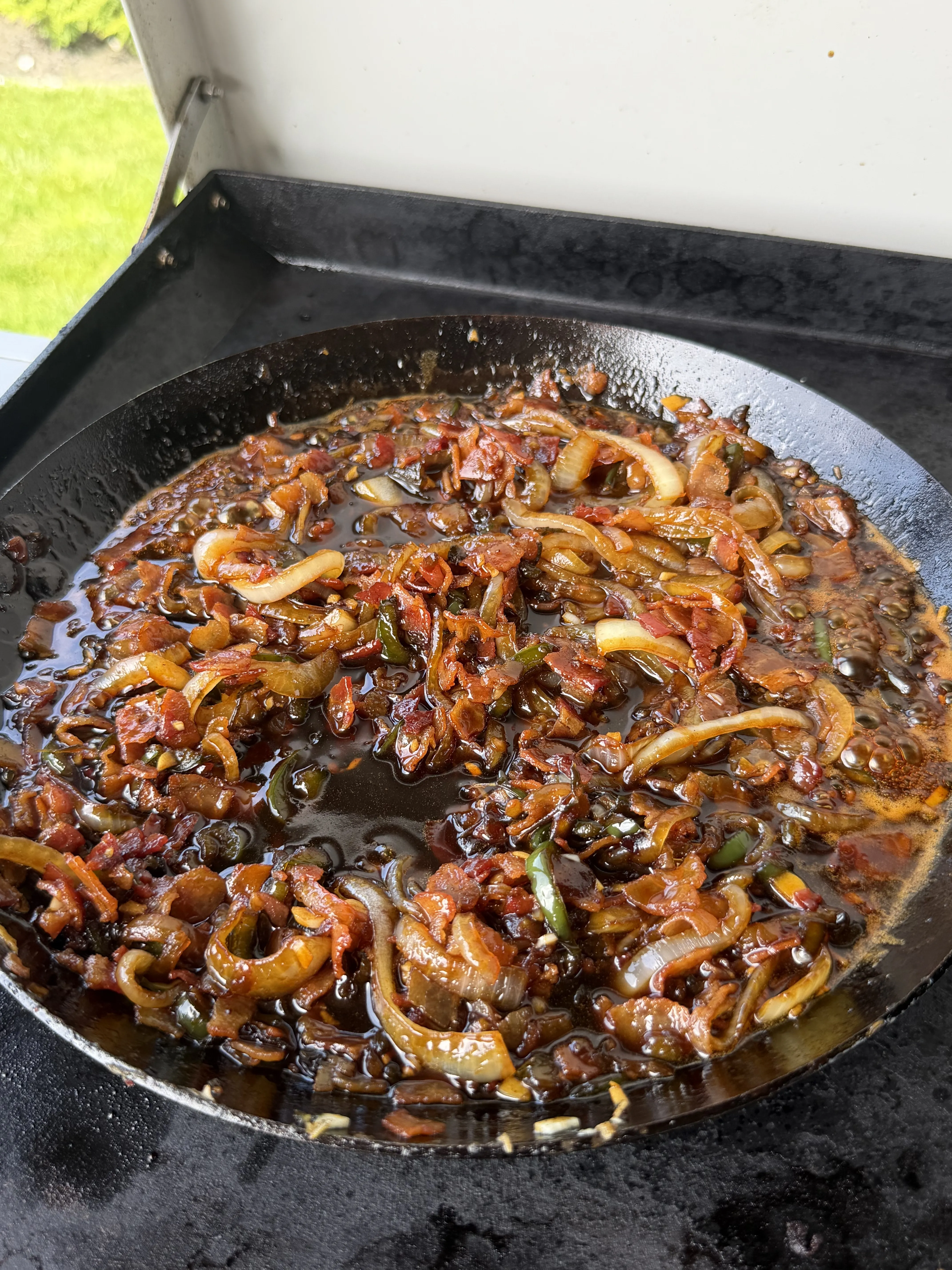 Caramelized bacon and onions cooking in a cast iron skillet for the molasses bacon jam