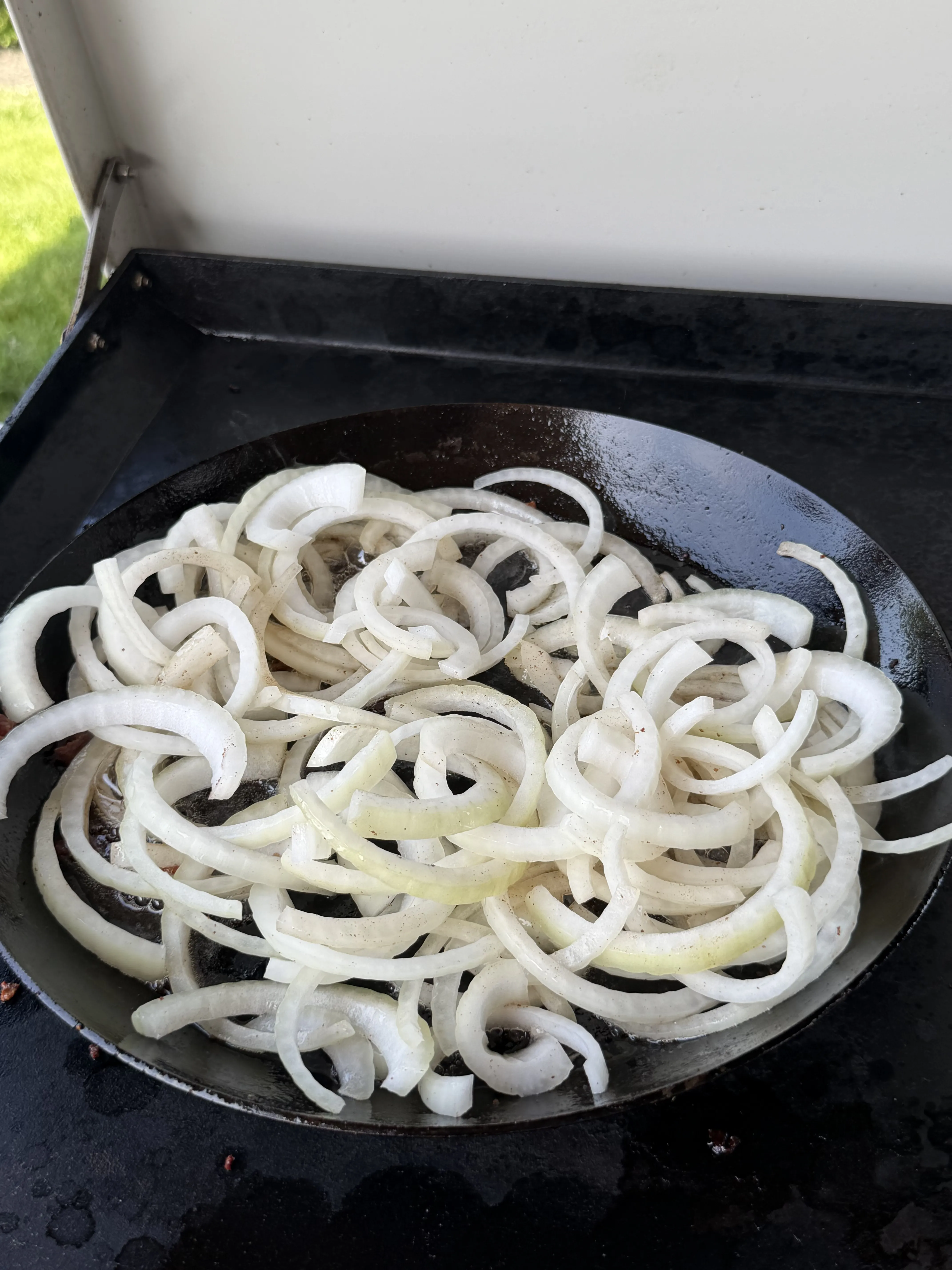 Sliced onions caramelizing in a cast iron skillet for patty melts