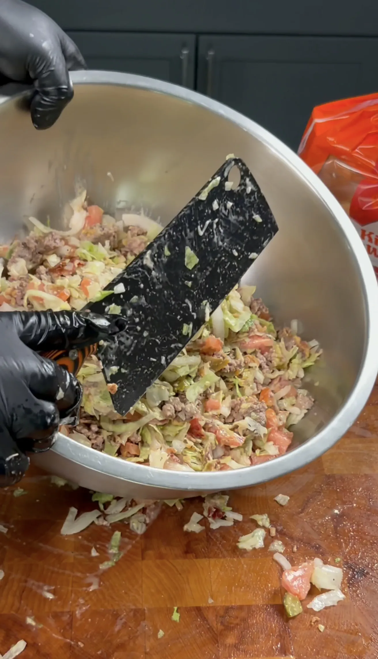 Chopped cheeseburger filling with lettuce and tomato being folded together