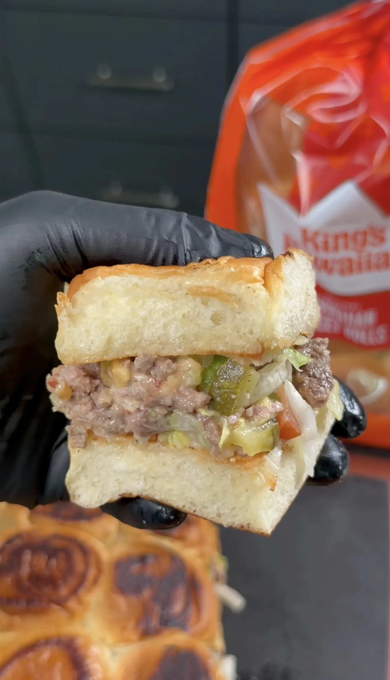 Hand holding a chopped cheeseburger slider on a toasted King's Hawaiian roll